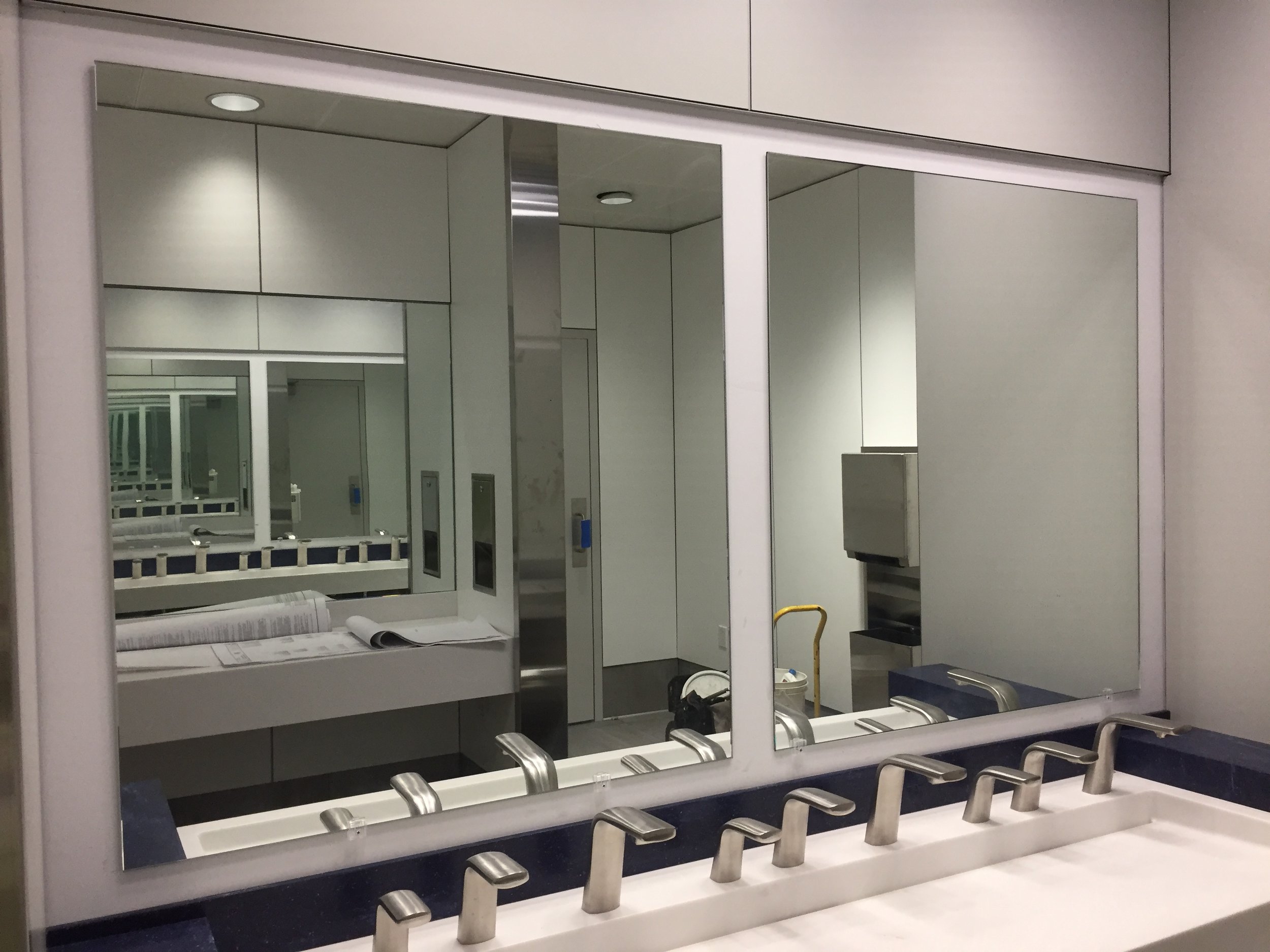 Empty airport baggage claim area with mirrors, chairs, and luggage carts.