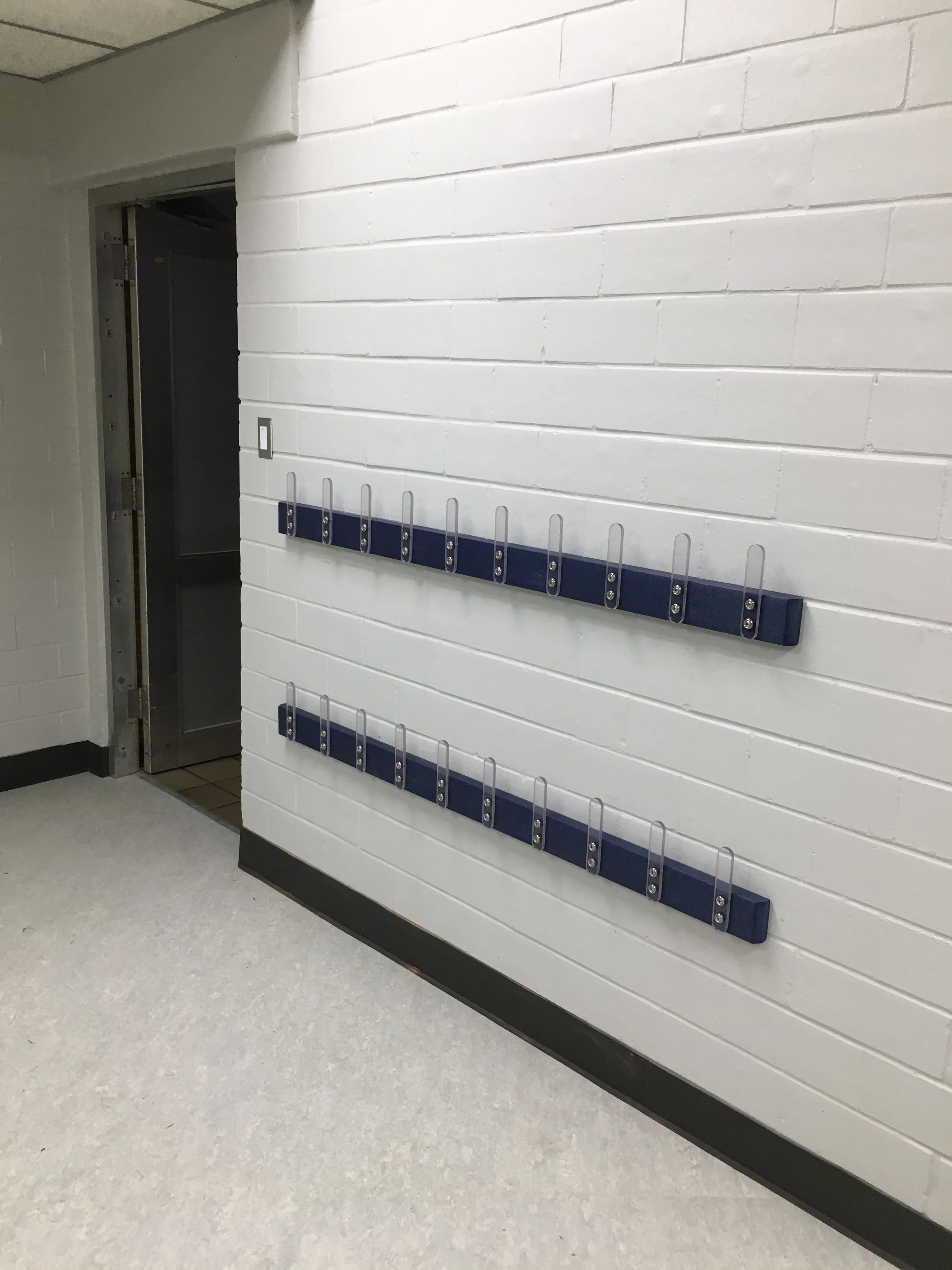 Empty wall with blue hooks for clothes or gear, next to an elevator