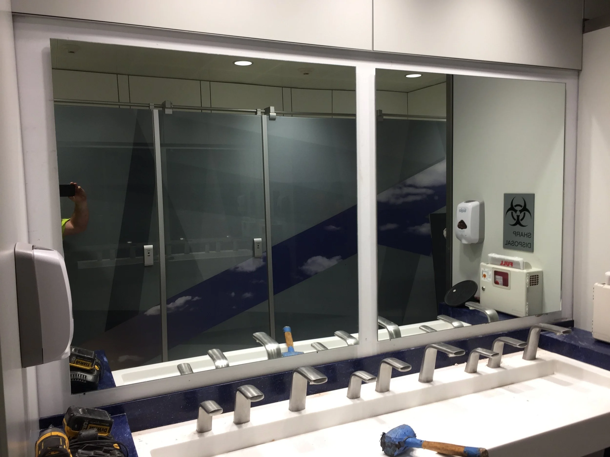 Hospital or airport departure gate with chairs, glass wall, and biohazard and hand sanitizer signs.