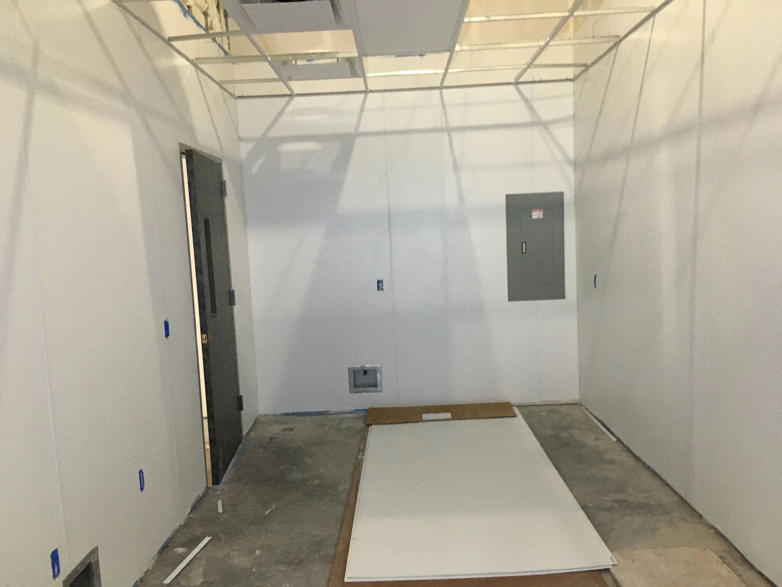 Construction area with unfinished drywall and an elevator door on the left, showing an environment under renovation or construction.