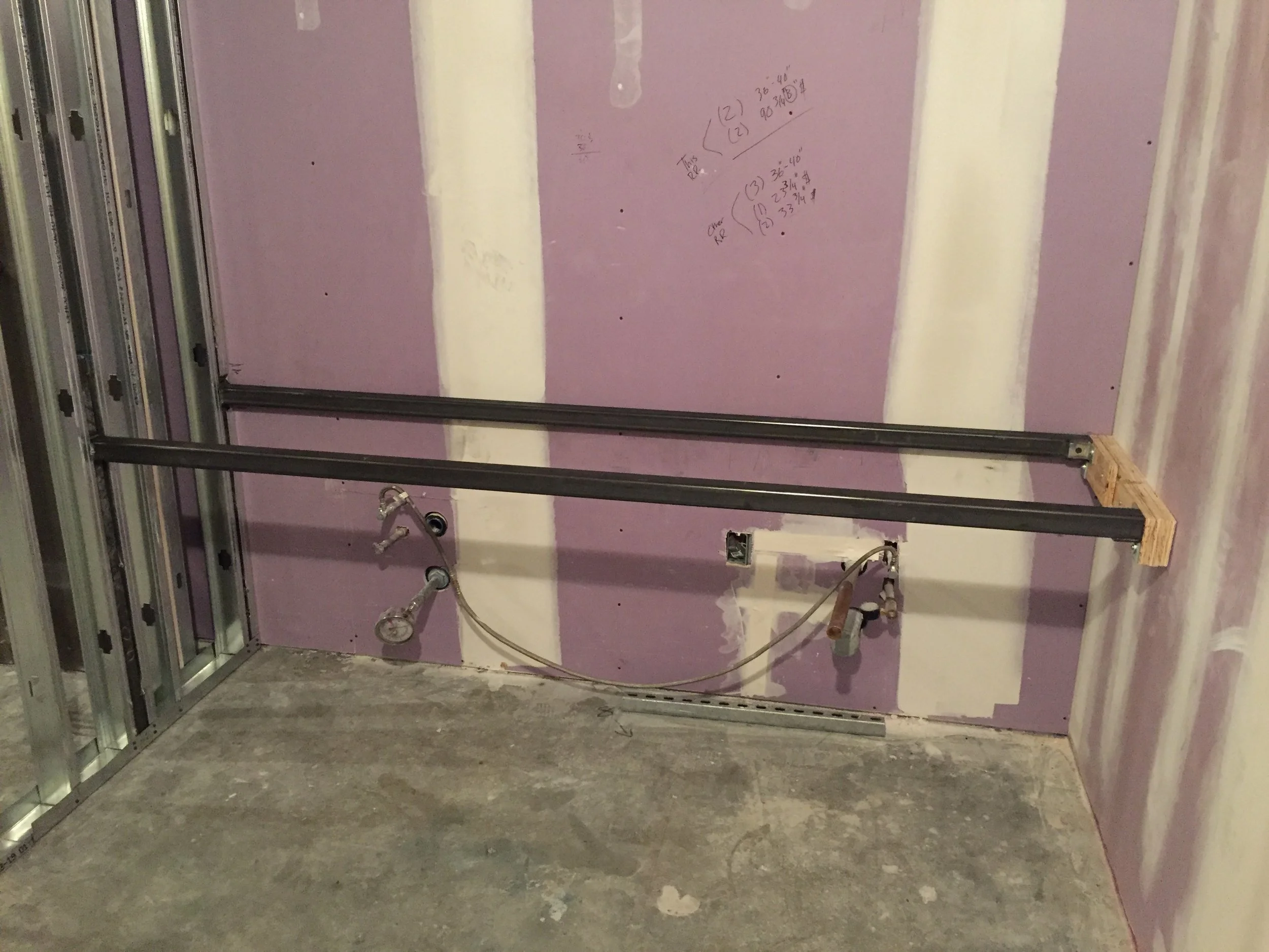 Construction site with interior drywall walls in process of being finished, with electrical wires and framing visible.