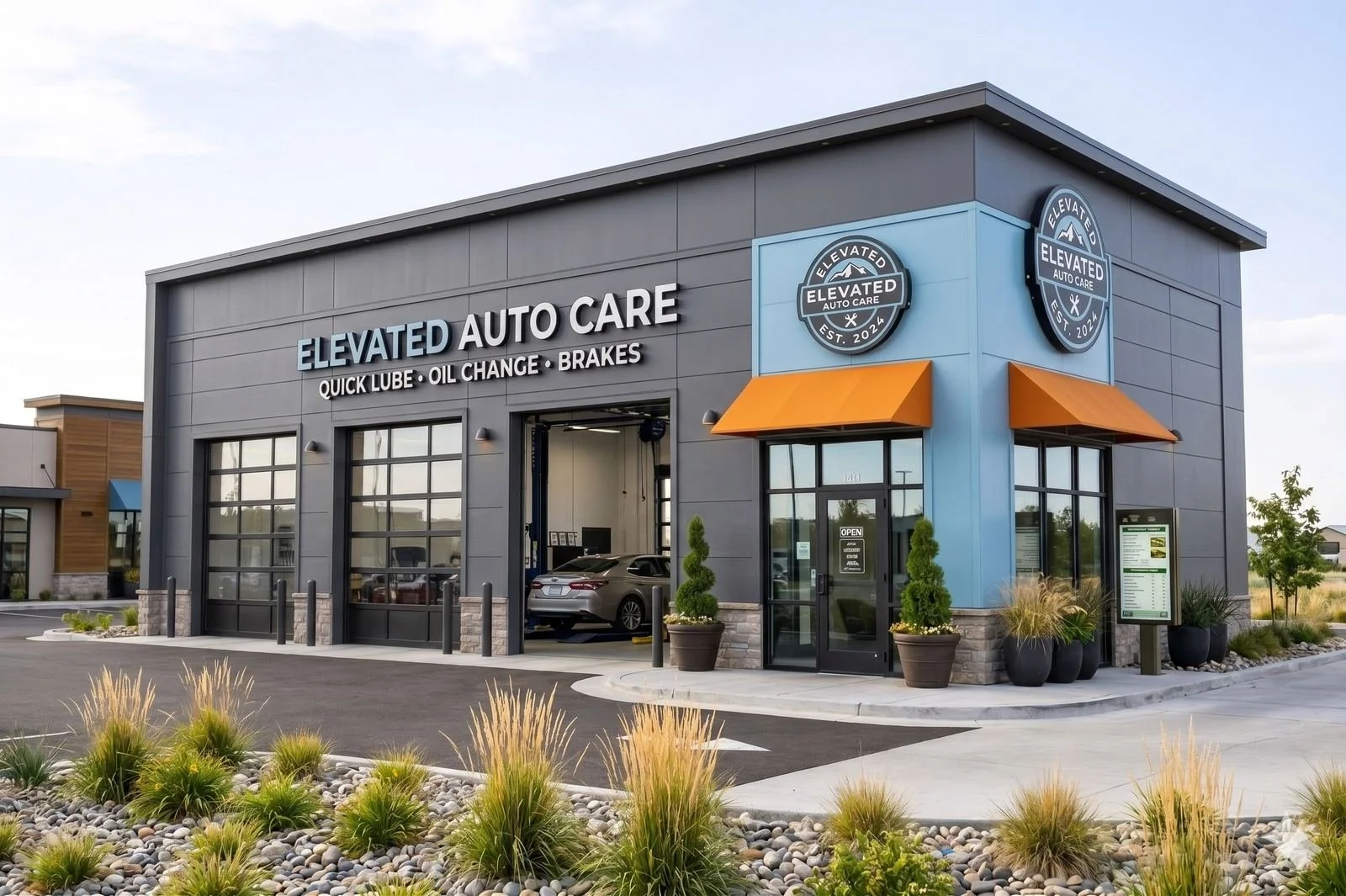 Gray building with sign that reads 'Elevated Auto Care' with orange awnings, plants, and a parked car inside. Large windows and parking lot in front.