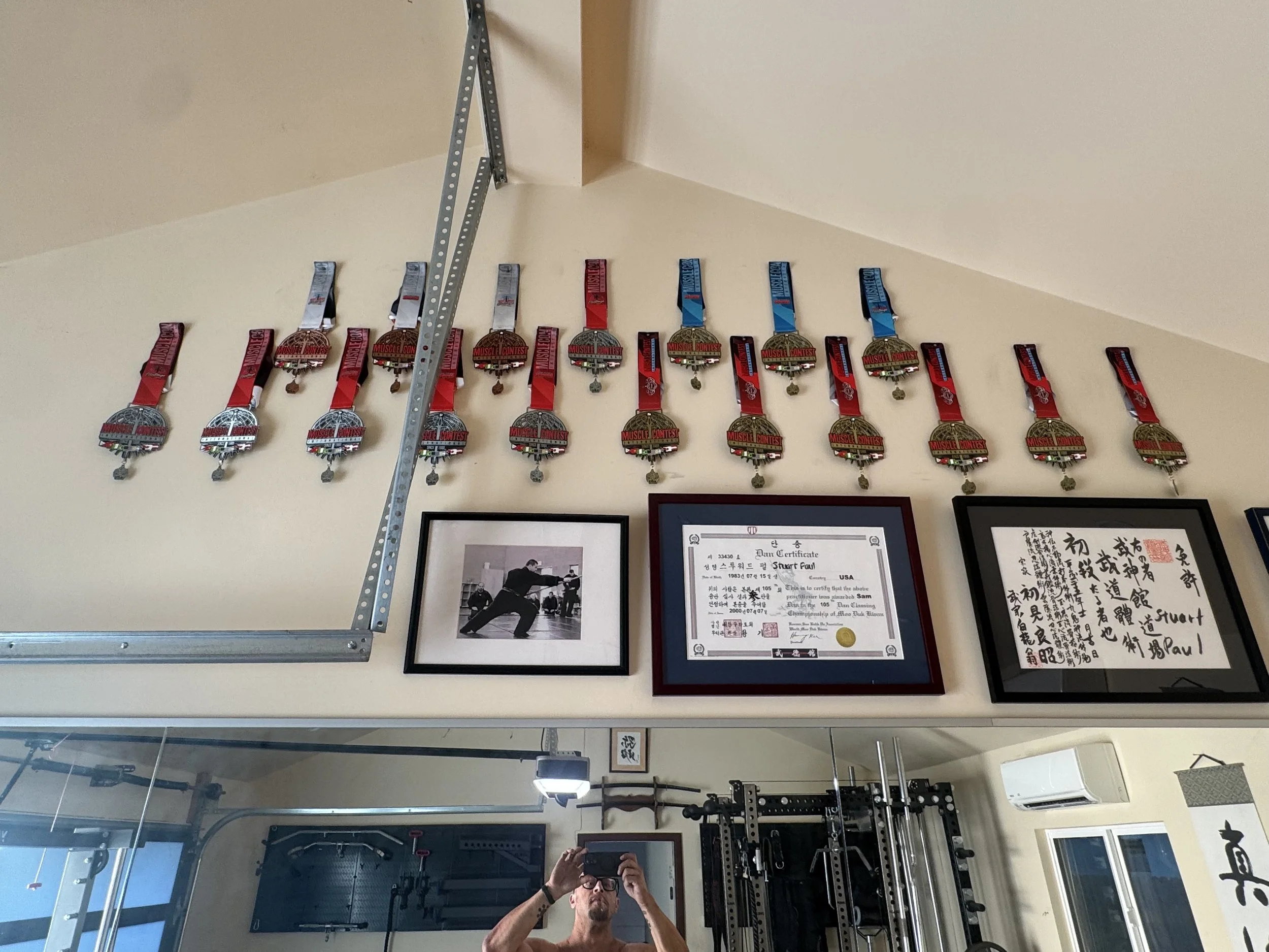 Wall display of bodybuilding competition medals at Toluca Lake studio