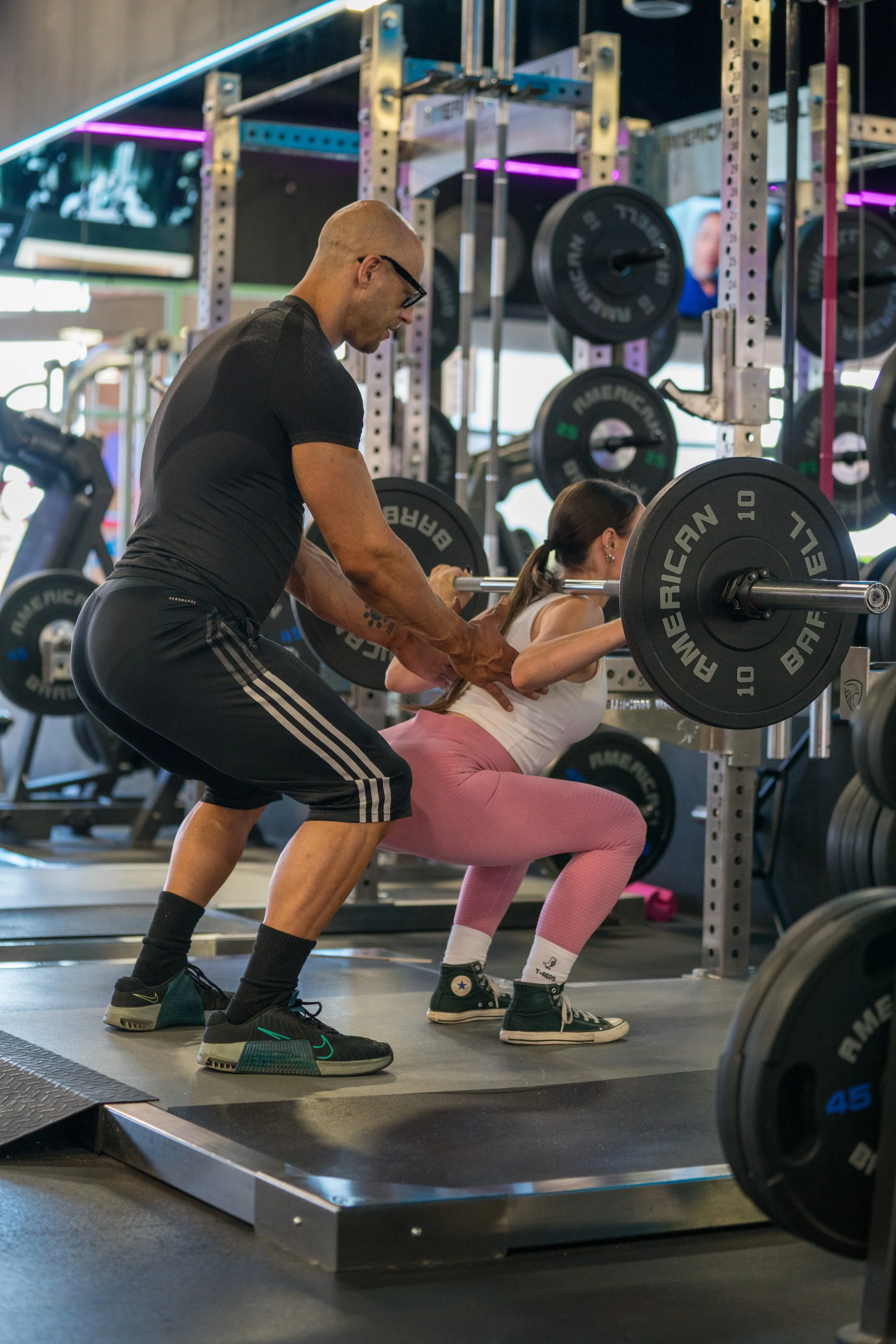 Personal trainer spotting client during squat exercise