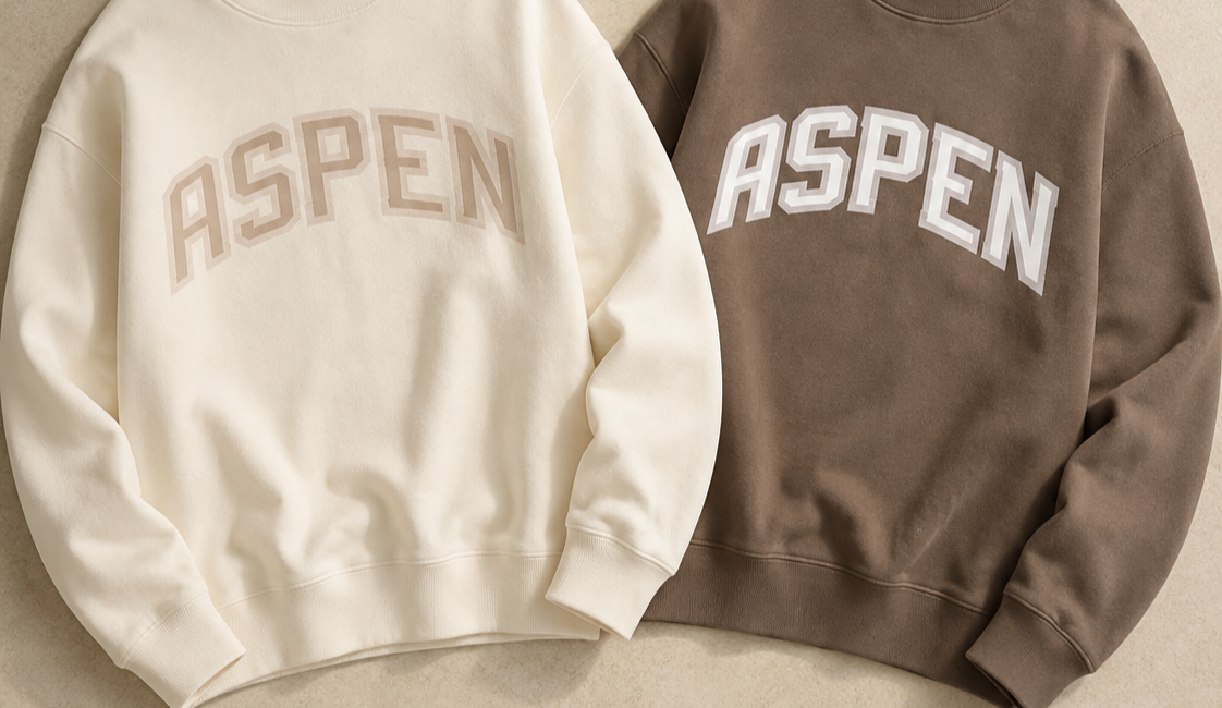Two sweatshirts, one white and one brown, with the word "ASPEN" printed on the front in large block letters.