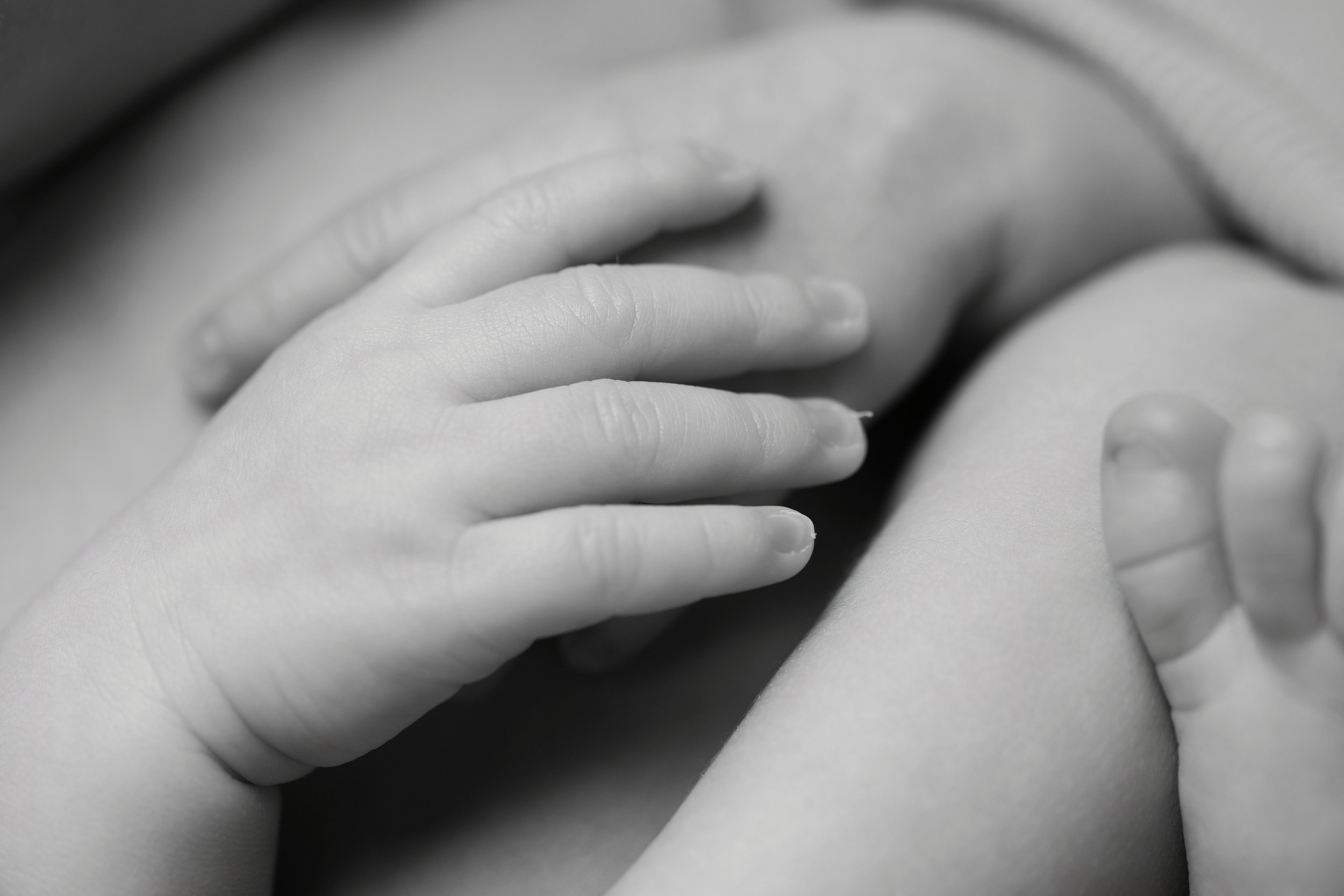 Close-up of a hand gently resting on a person's torso, in black and white.