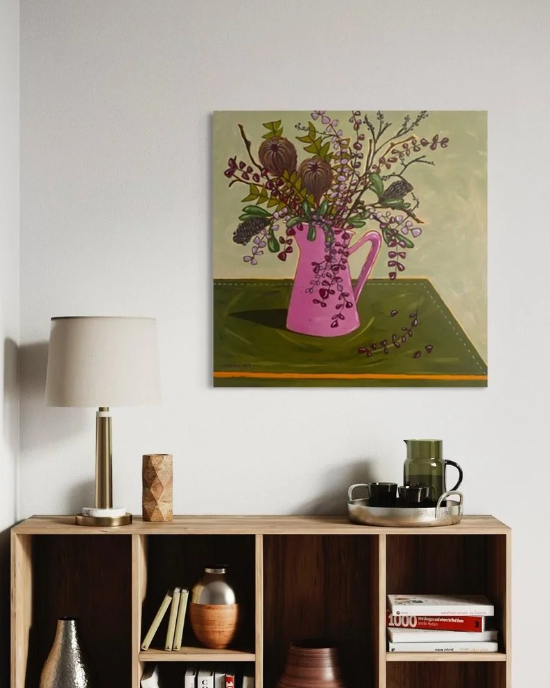 Still life painting of a pink jug holding banksia pods and berry stems on a green table, hung above a sideboard. View Kaz Hughes on Instagram