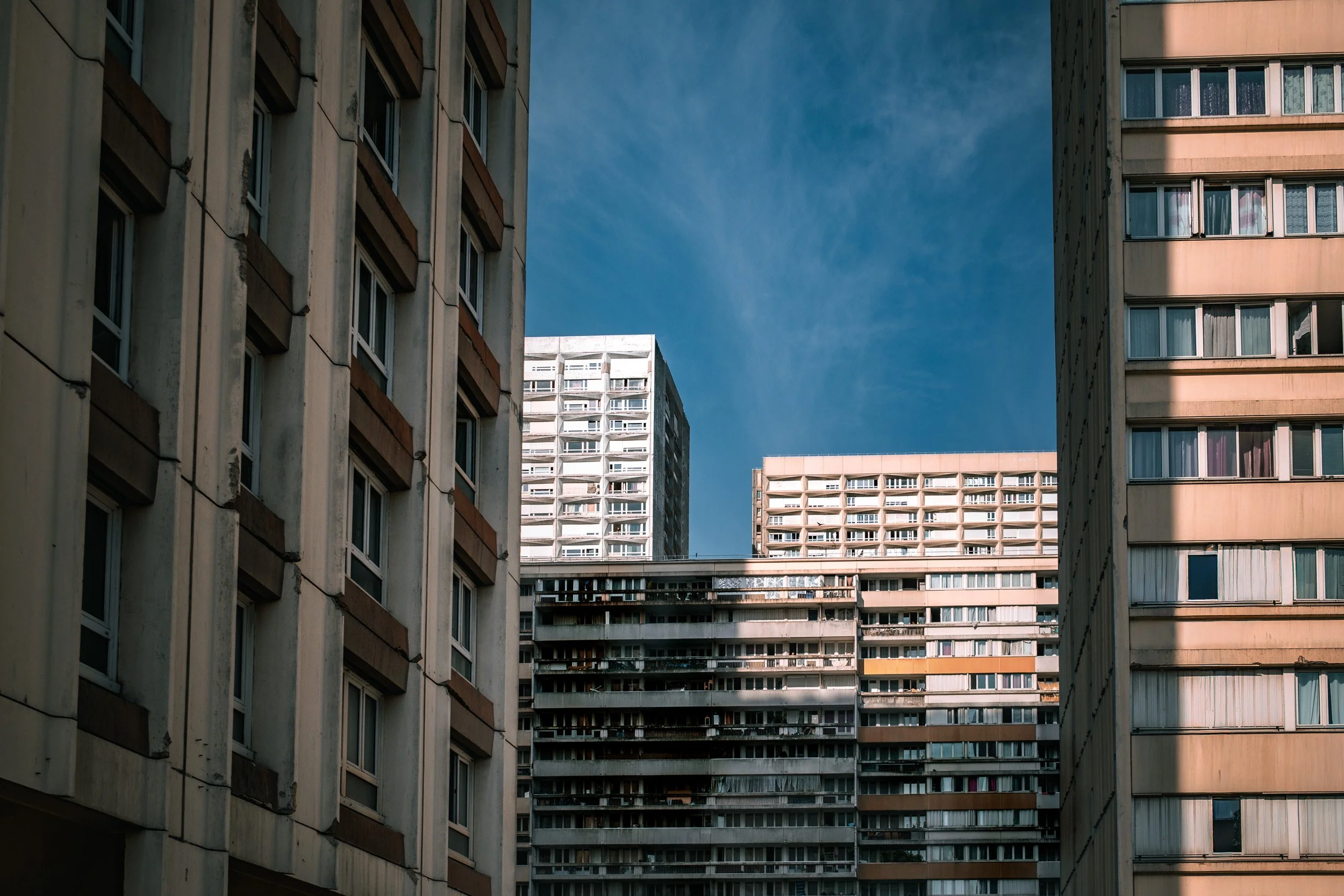 Dense residential towers frame a patch of deep blue sky in a layered urban composition.