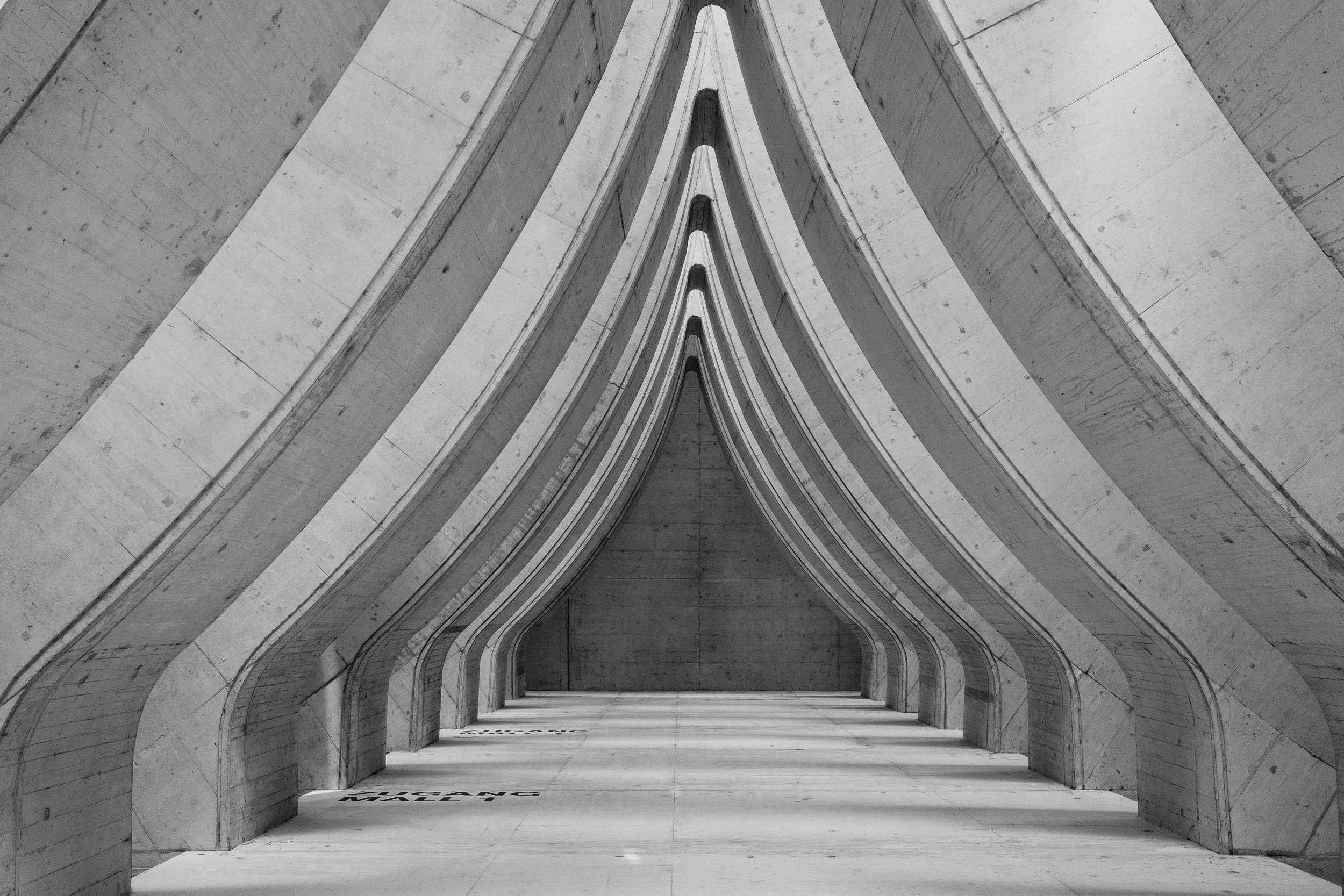Repeating pointed concrete arches form a symmetrical black-and-white passage.