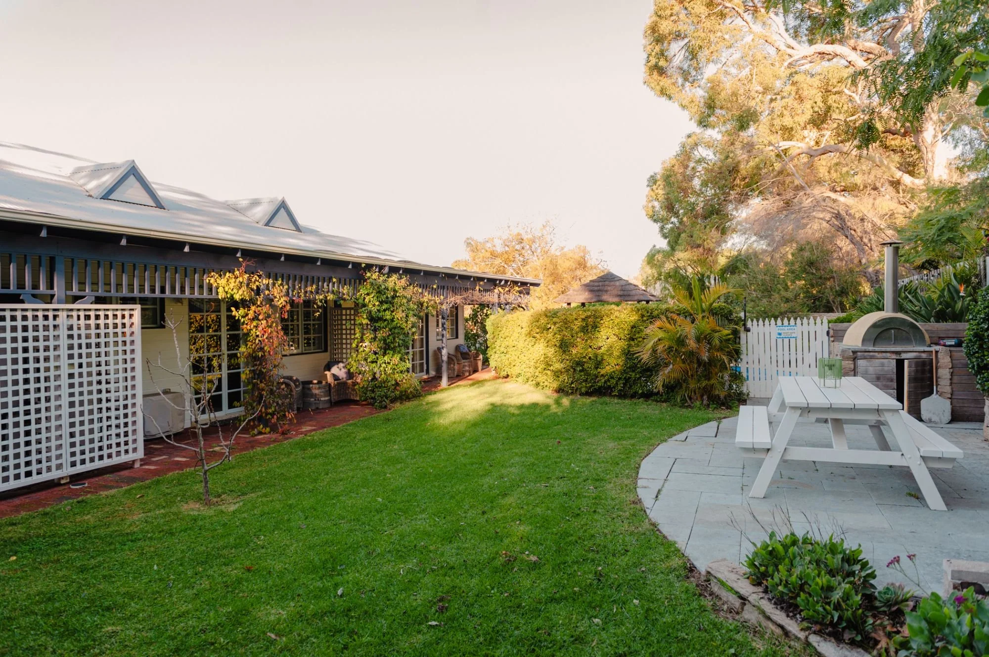 Lanterns Retreat backyard with a lush green lawn, a white picnic table, and a patio area with a firepit.