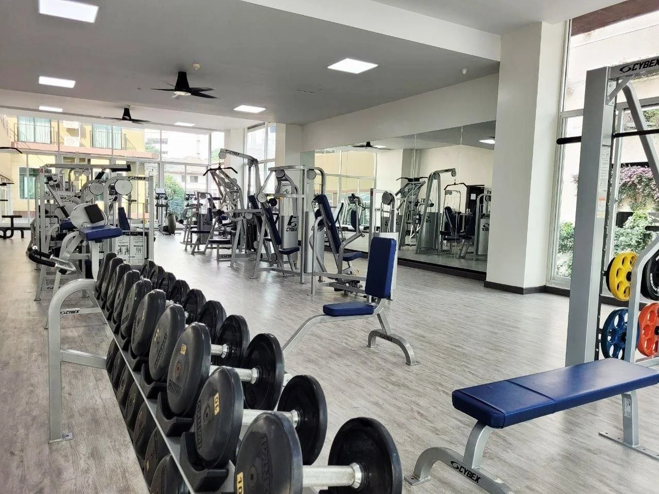 Empty gym with various weightlifting equipment, benches, and mirrors.