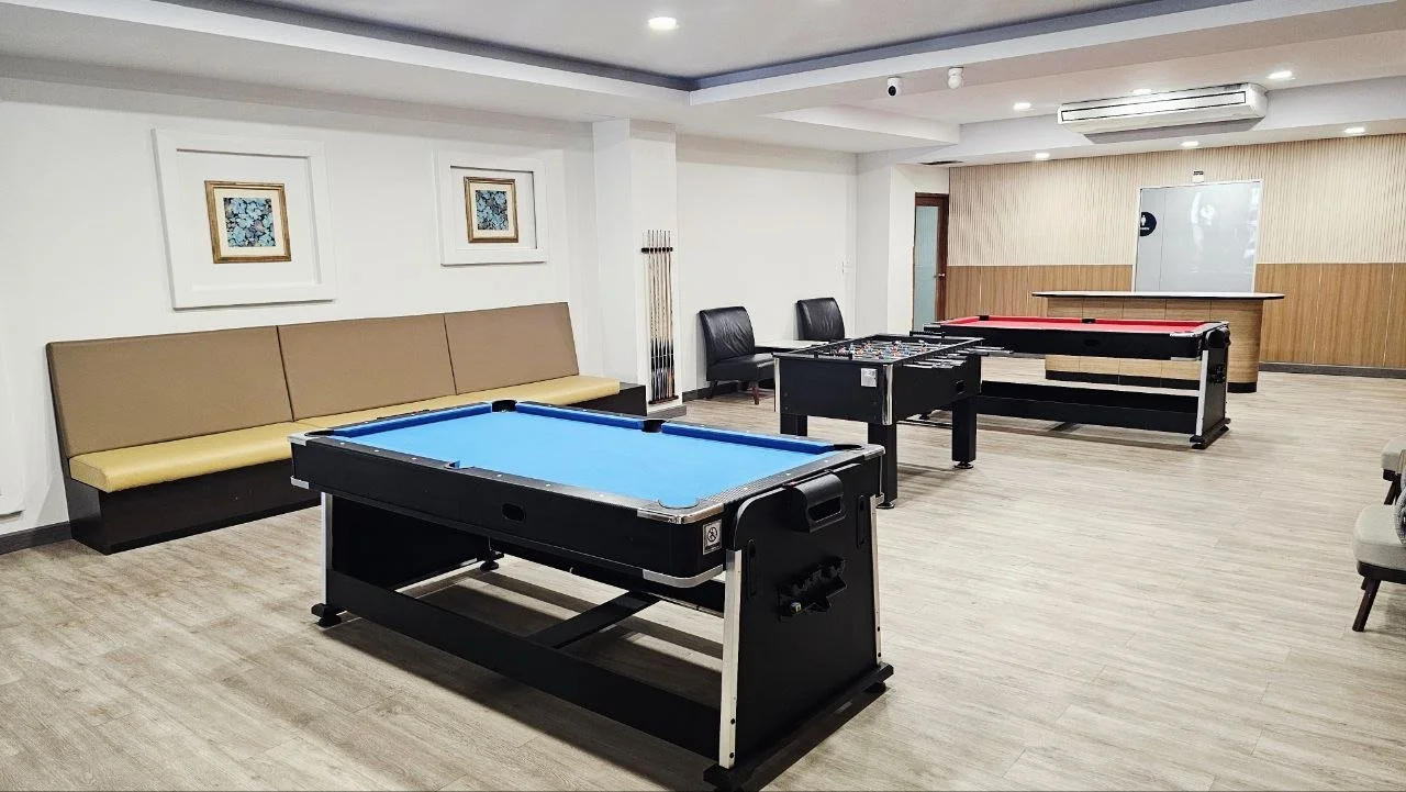 An indoor recreational room with two pool tables, a foosball table, and seating area.
