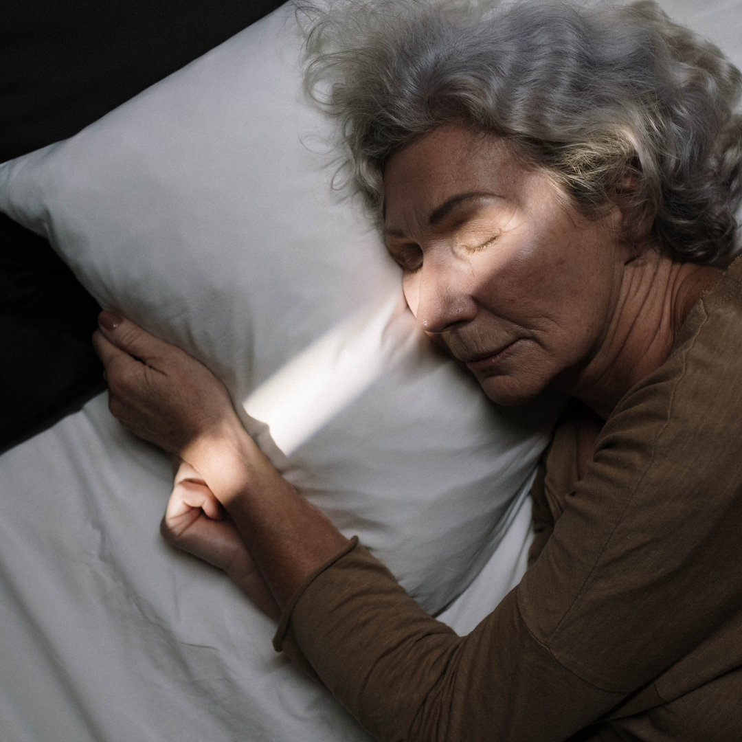 Woman sleeping peacefully in bed, illustrating the restful bedroom environment a geopathic stress survey aims to support