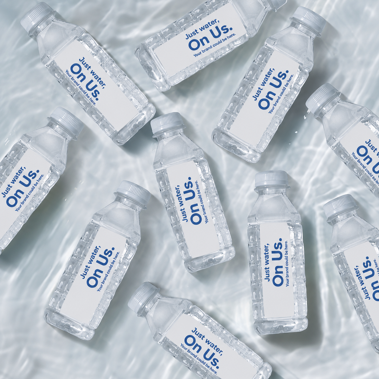 Multiple clear plastic water bottles with white caps and blank labels that say 'Just water, On Us. Your brand could be here.' arranged on a wavy light surface.