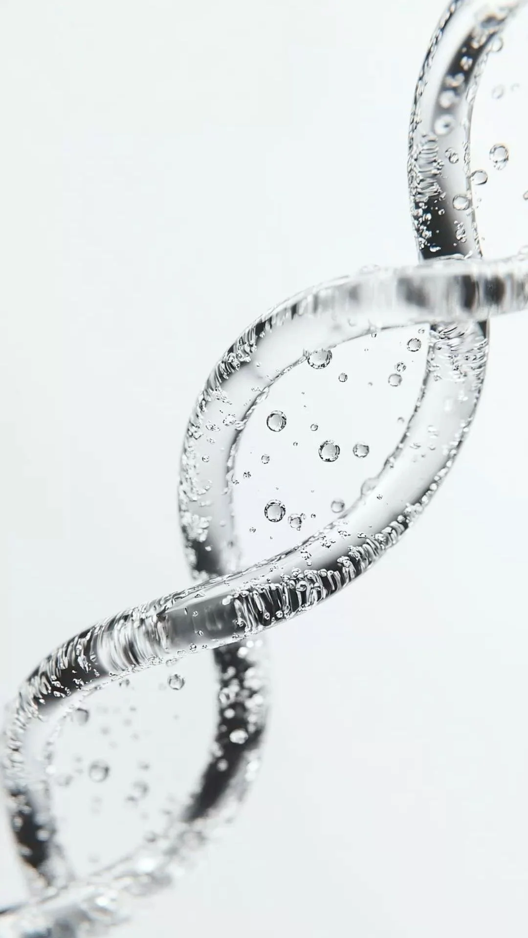 Close-up of a flexible, transparent tube with small bubbles of air or gas suspended inside, set against a plain white background.