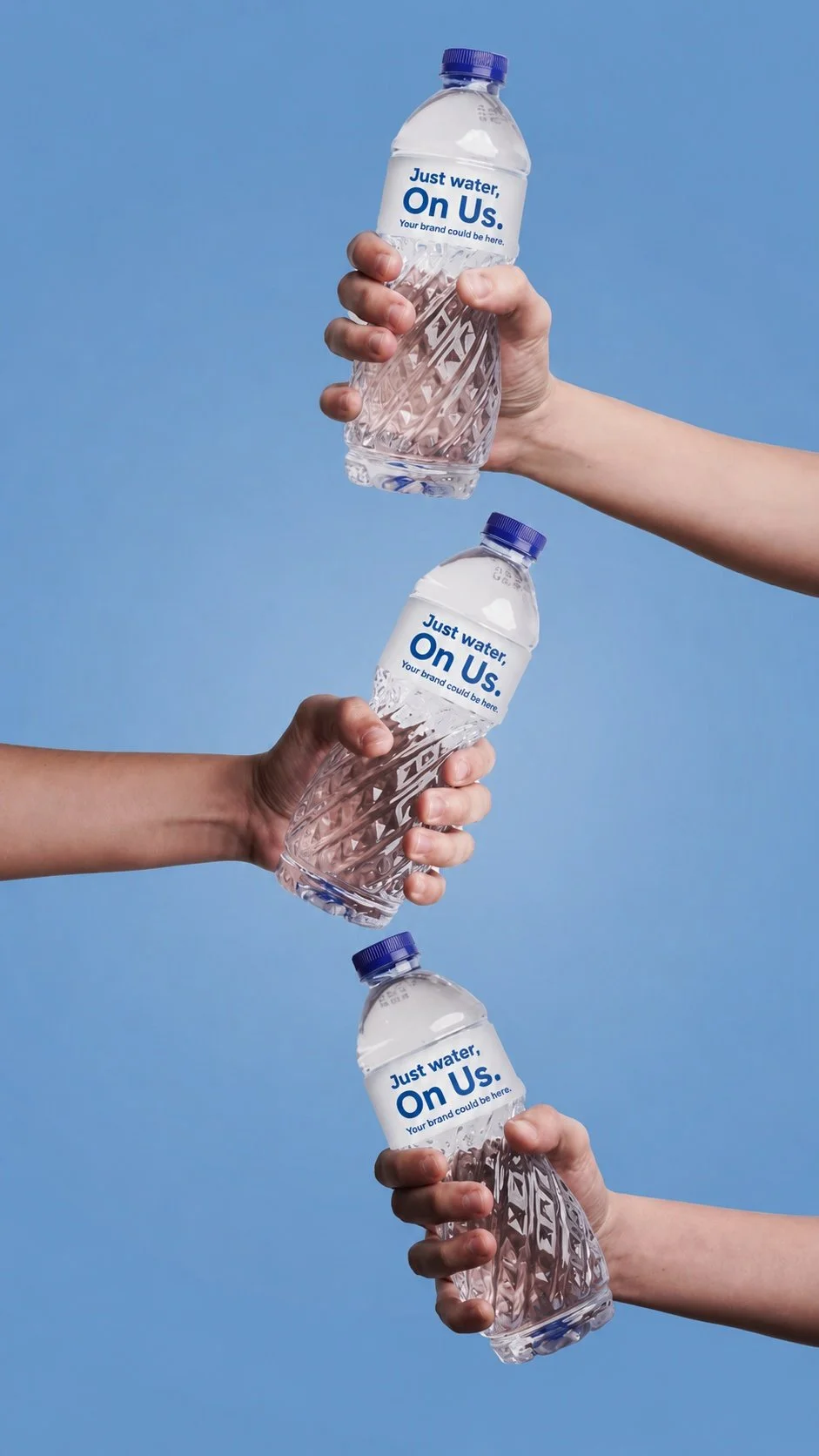 Three hands holding bottles of water against a blue background, with labels reading 'Just water, On Us. Your brand could be here.'