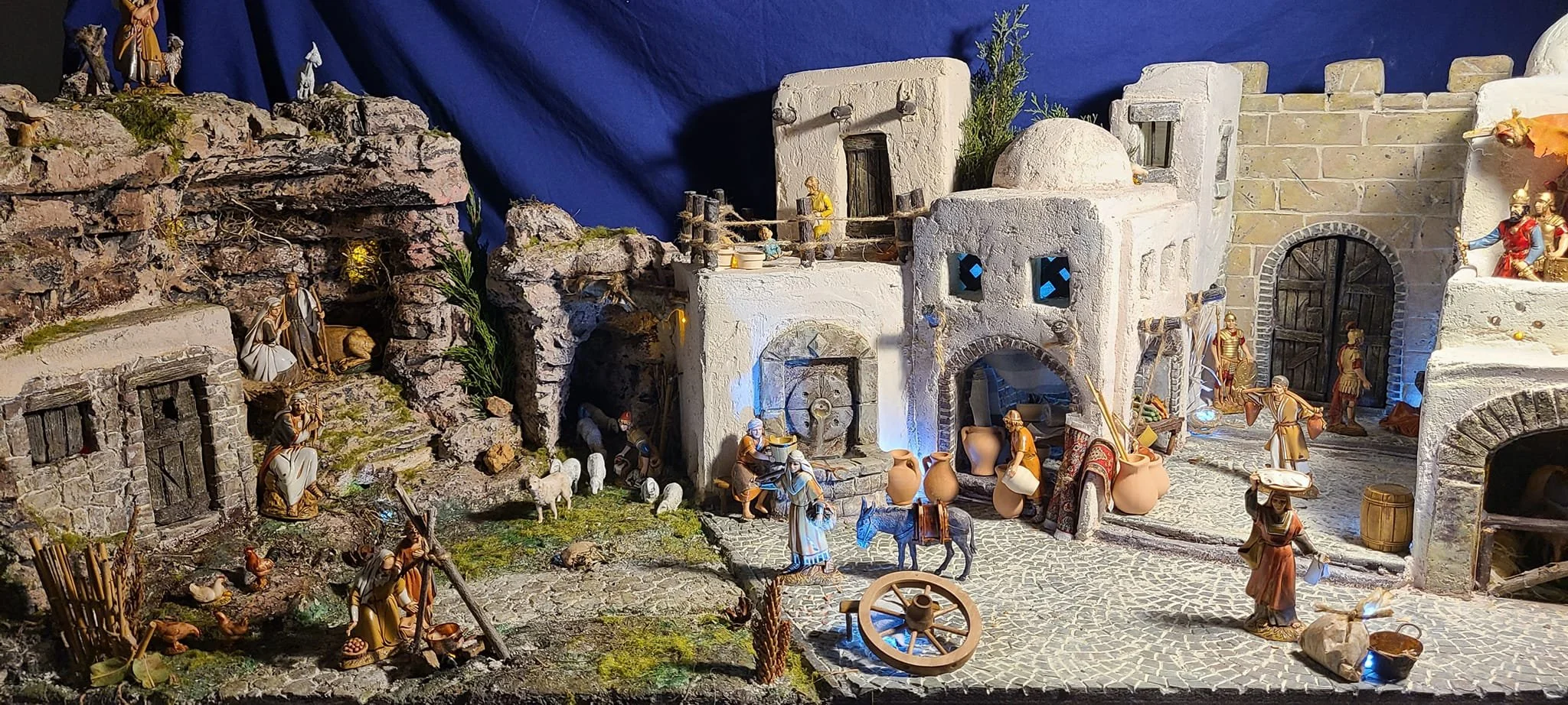 Presepe natalizio con miniature di case antiche, pastori, animali e figure della Natività in un paesaggio rurale
