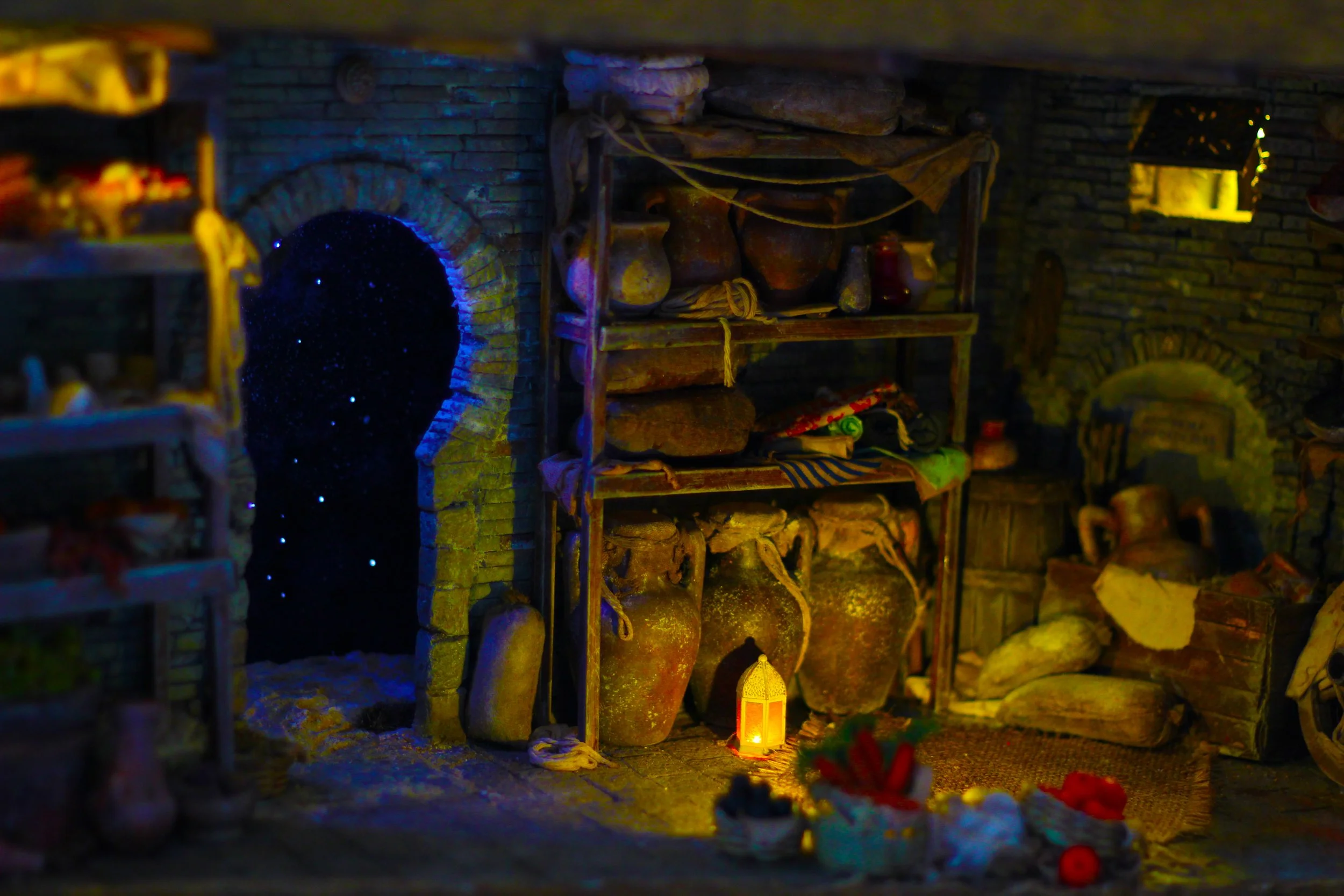 Scaffale in una stanza con mattoni, pieni di antichi vasi di terracotta, tessuti e altri oggetti, illuminata da luci calde e un'illuminazione blu, con un'apertura ad arco nel muro.