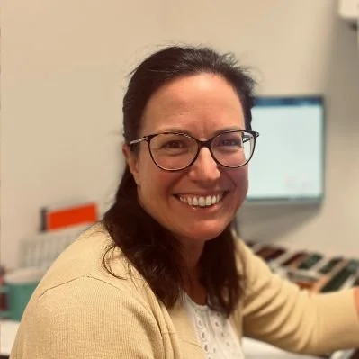Libby Raison smiling in an office, with a computer monitor in the background.