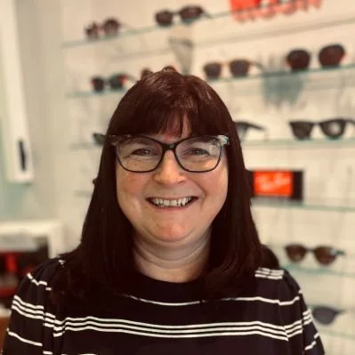 Michelle Stubley in front of a display of sunglasses on shelves.