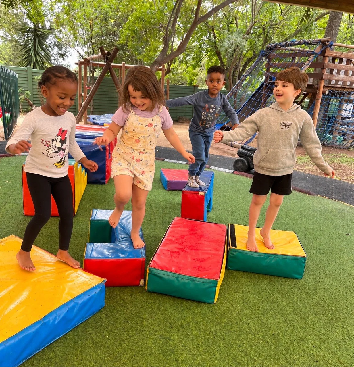 Two children playing on a playground slide, with a boy at the bottom and a girl climbing up behind him, both smiling and enjoying outdoor activity.