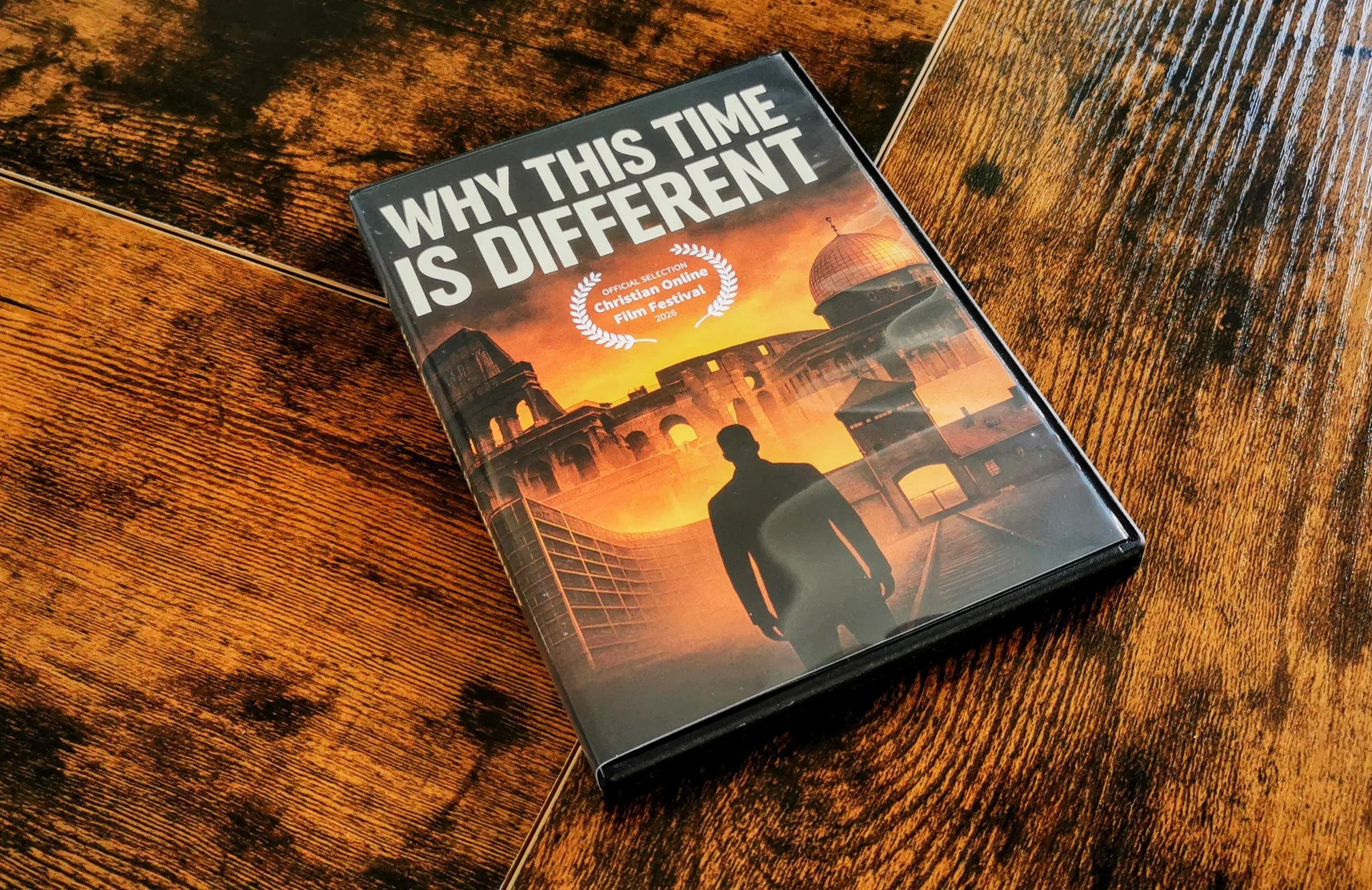 木の机の上に置かれた映画のDVDケースで、タイトルは「WHY THIS TIME IS DIFFERENT」と書かれている。