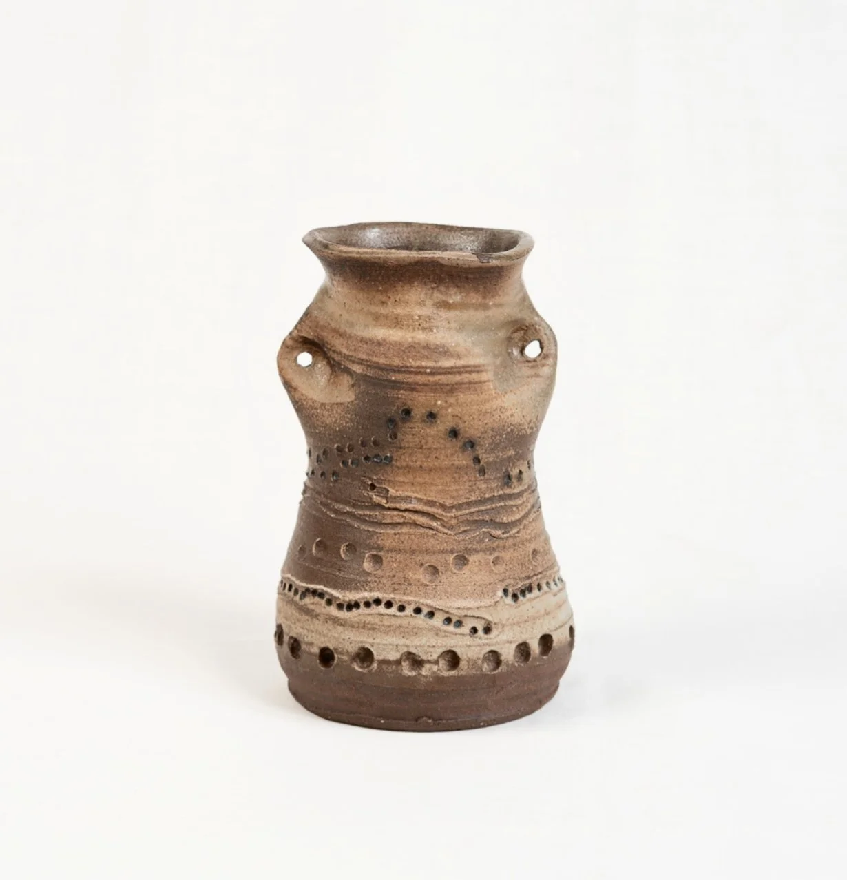 An ancient-style clay pottery vessel with decorative perforations and patterns, against a plain white background.