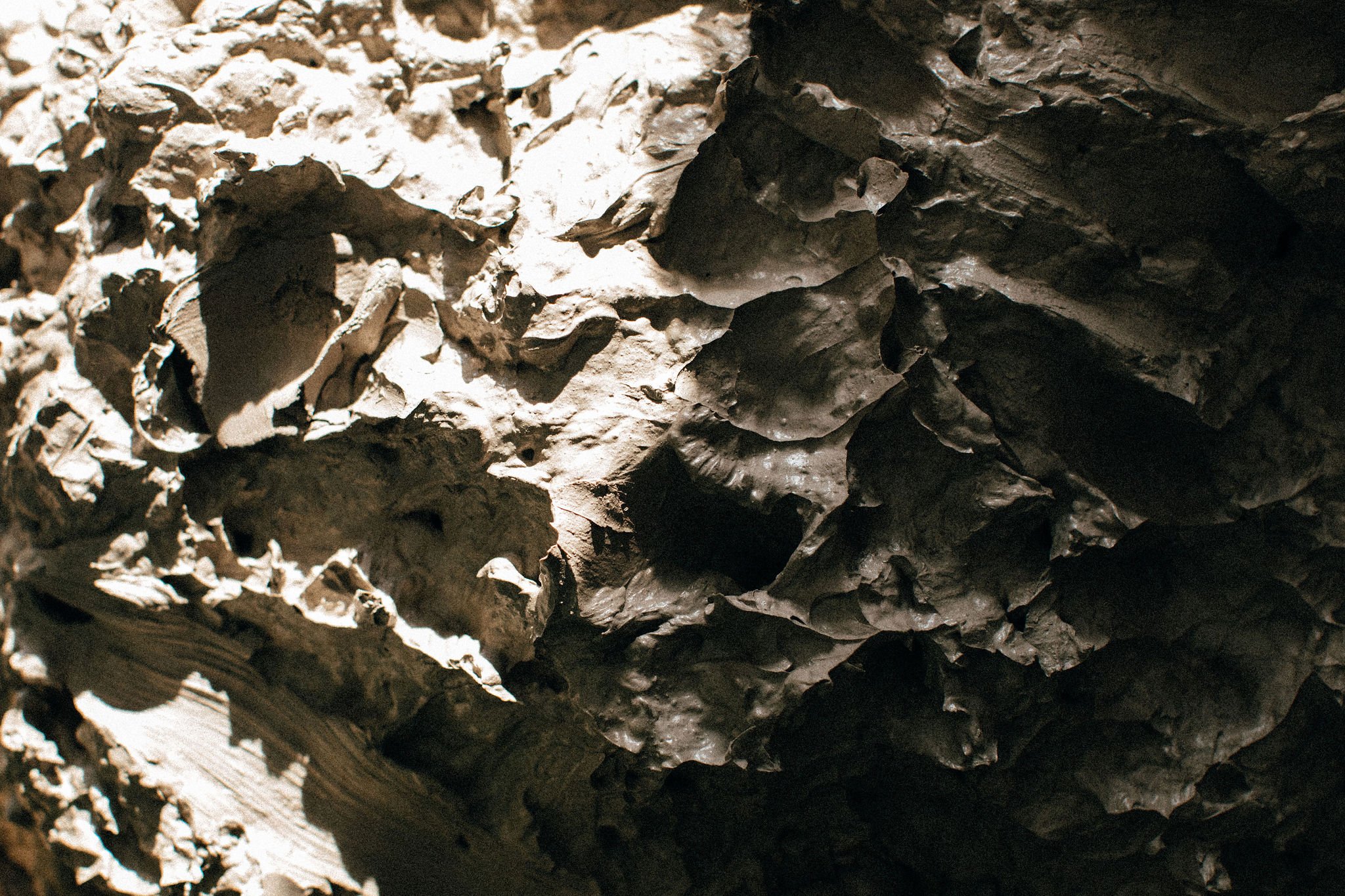 Close-up of a textured, dimpled clay reclaim surface with sun over half and shadow over the other half.