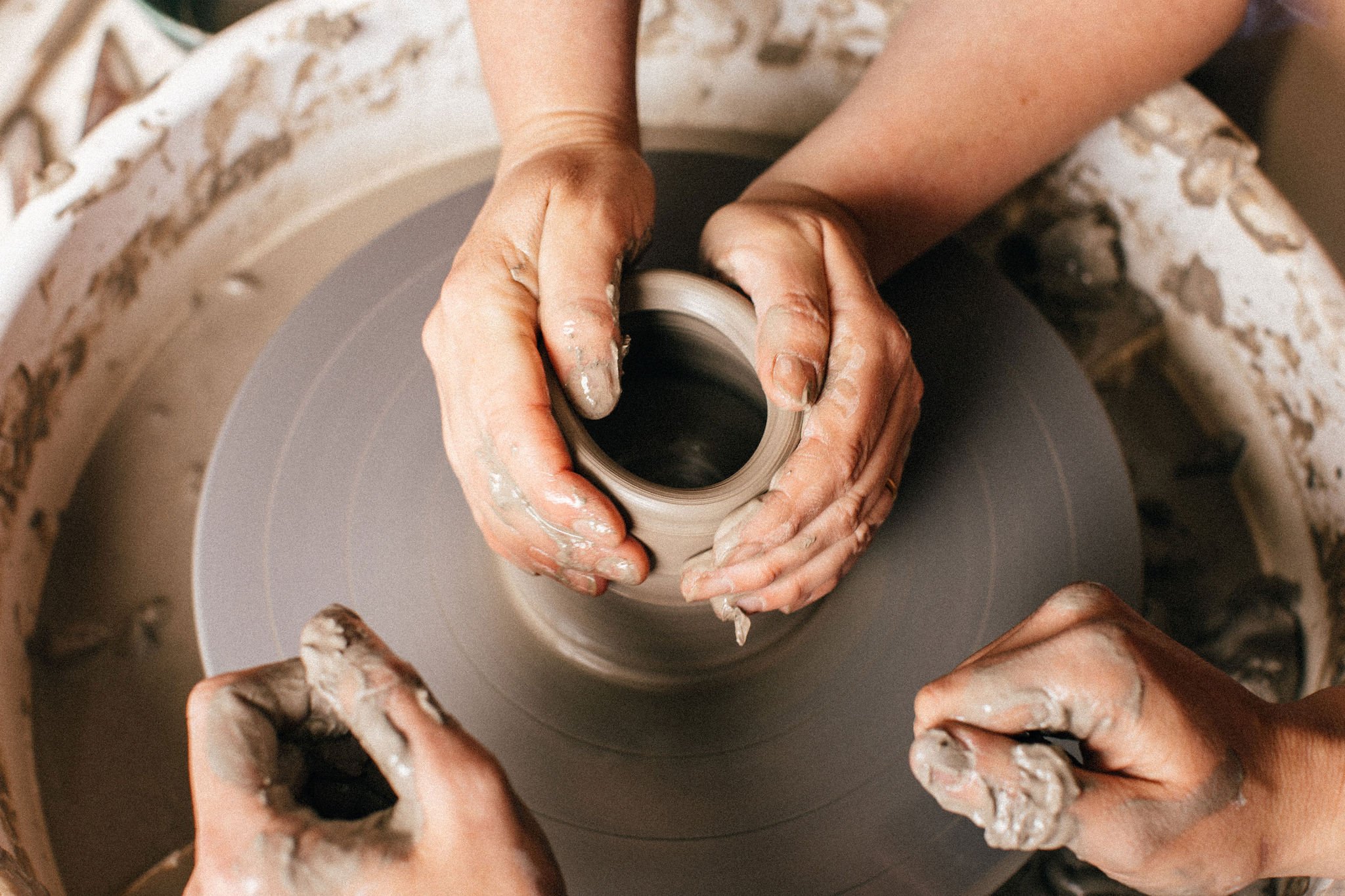 Hands shaping clay on a pottery wheel.