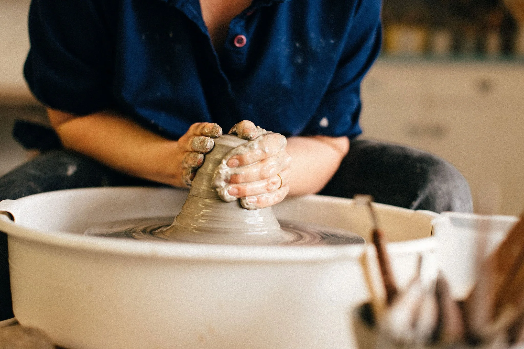 Person shaping clay on a pottery wheel
