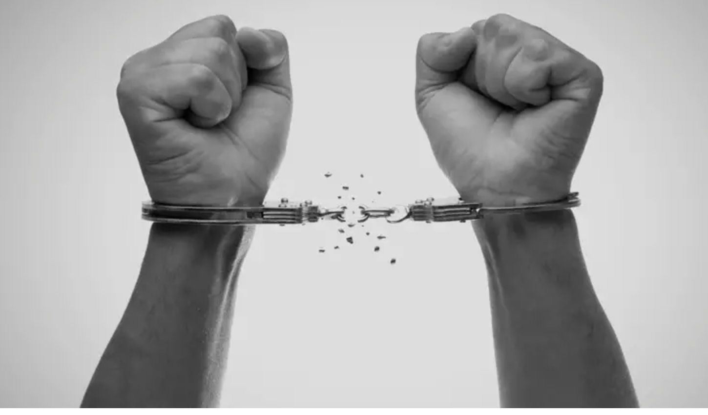 Two clenched fists with broken handcuffs, symbolizing breaking free from captivity.
