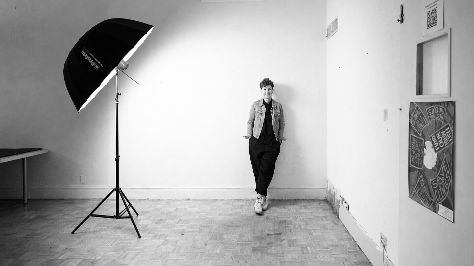 Bianca Weber leaning against a studio wall in a black-and-white portrait.