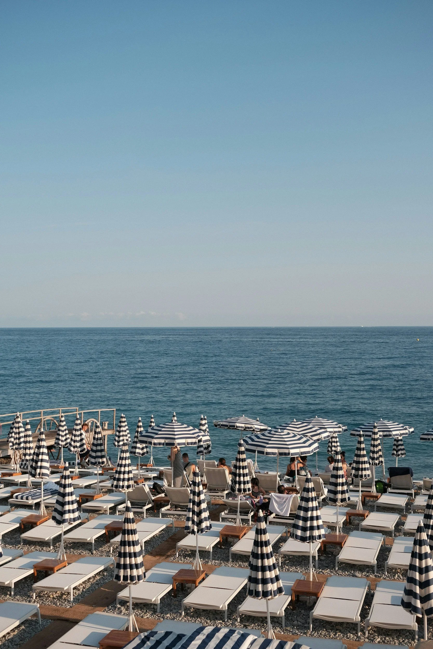 Strand mit blau-weiß gestreiften Sonnenschirmen und Liegen an der Côte d'Azur