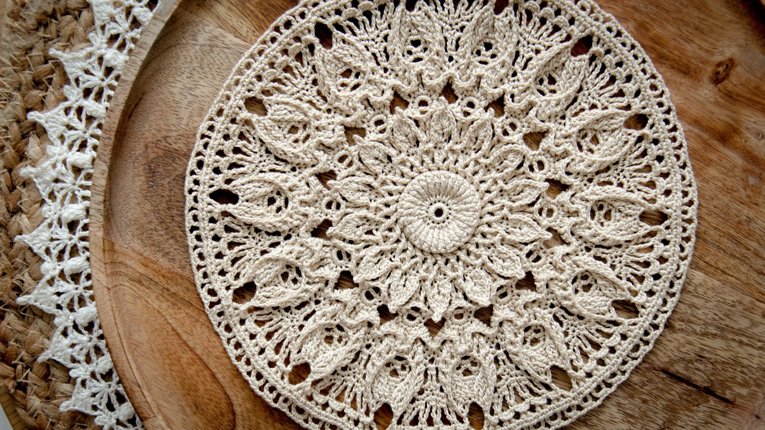 Olga crochet doily in natural beige, shown on a wooden tray with intricate floral lace details.