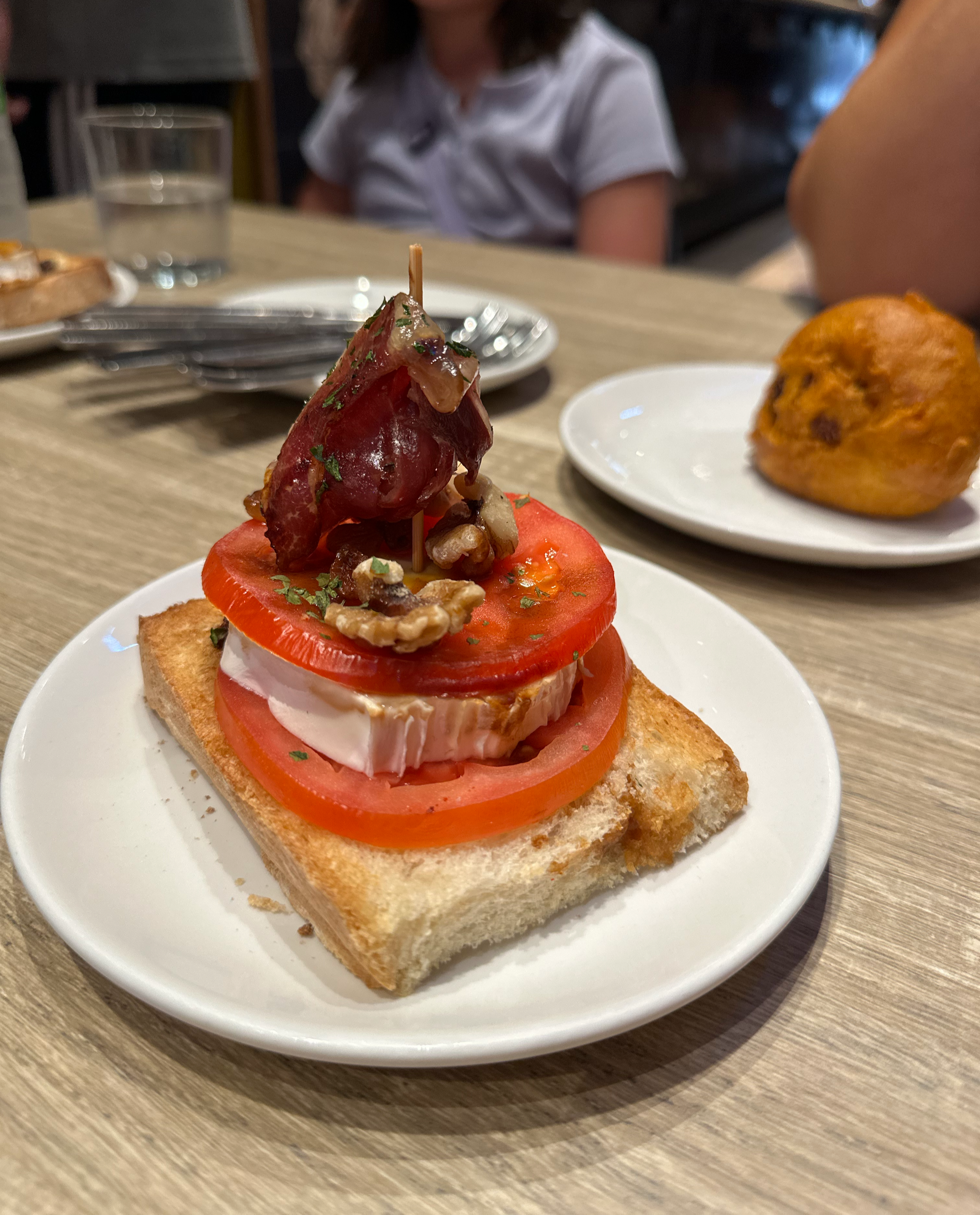 One of our favorites.  Toasted bread with sliced tomato, brie, walnuts, iberico ham, and balsamic. And in the background a croquette.