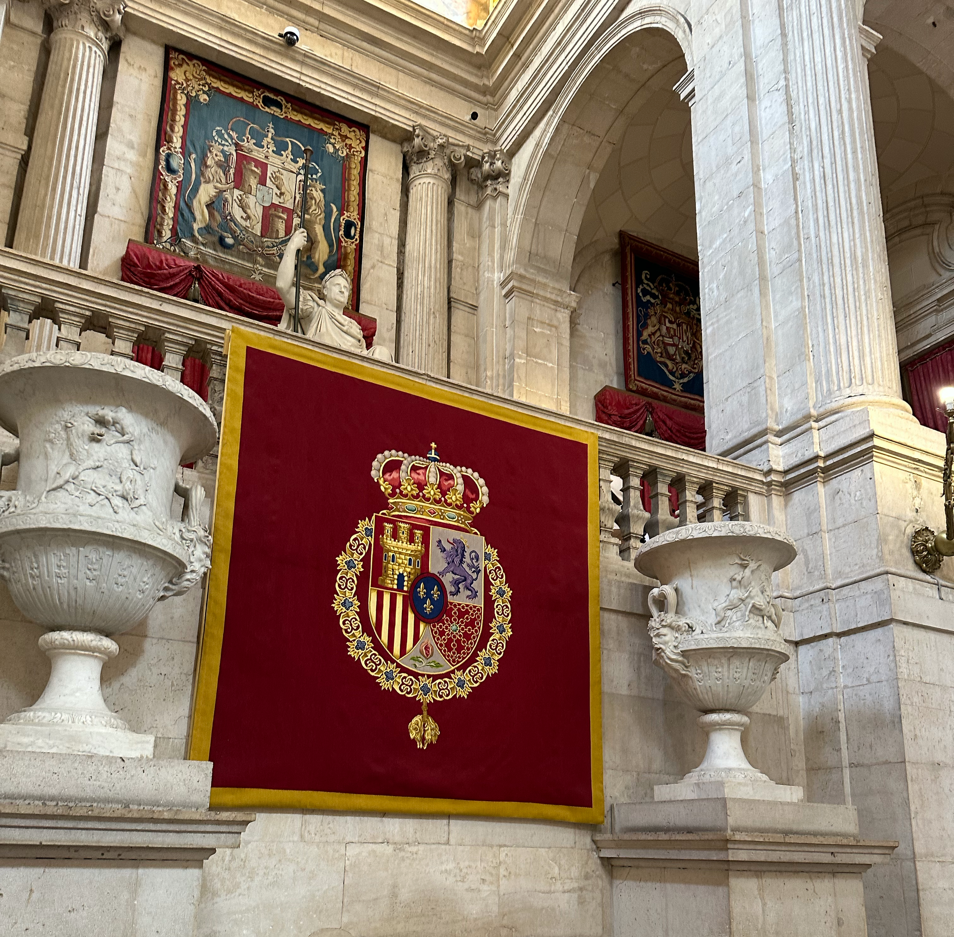 The tapestry above shows the Coat of Arms of Spain and the tapestry below is the Coat of Arms of the King of Spain. 