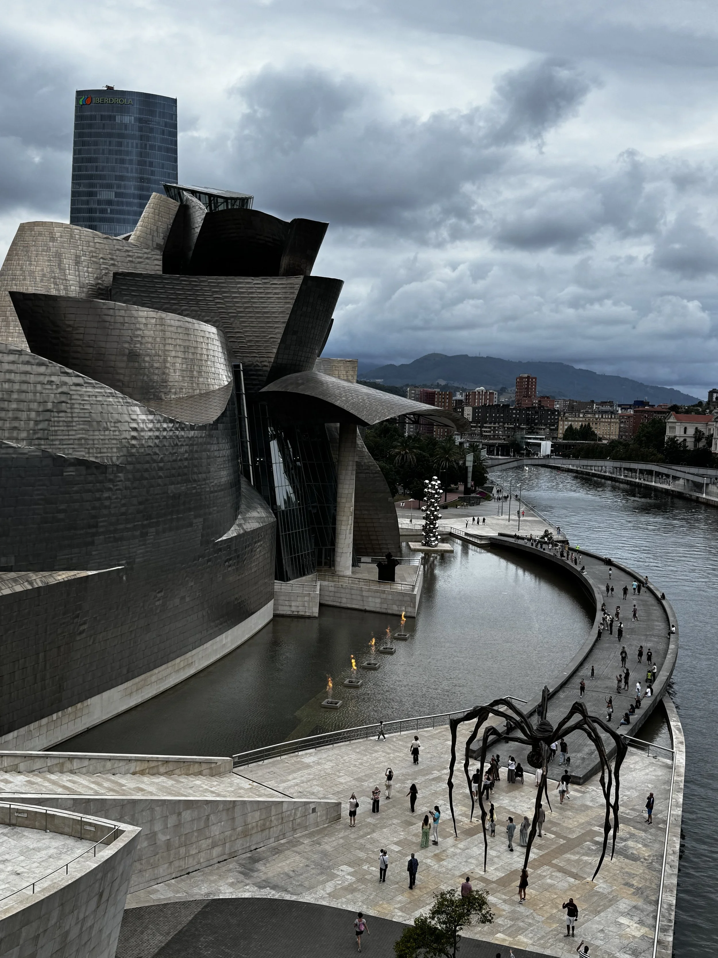 The Guggenheim Museum in Bilbao seen from the bridge crossing the river.  Also, the "Fire Fountain" lit up as we were crossing!