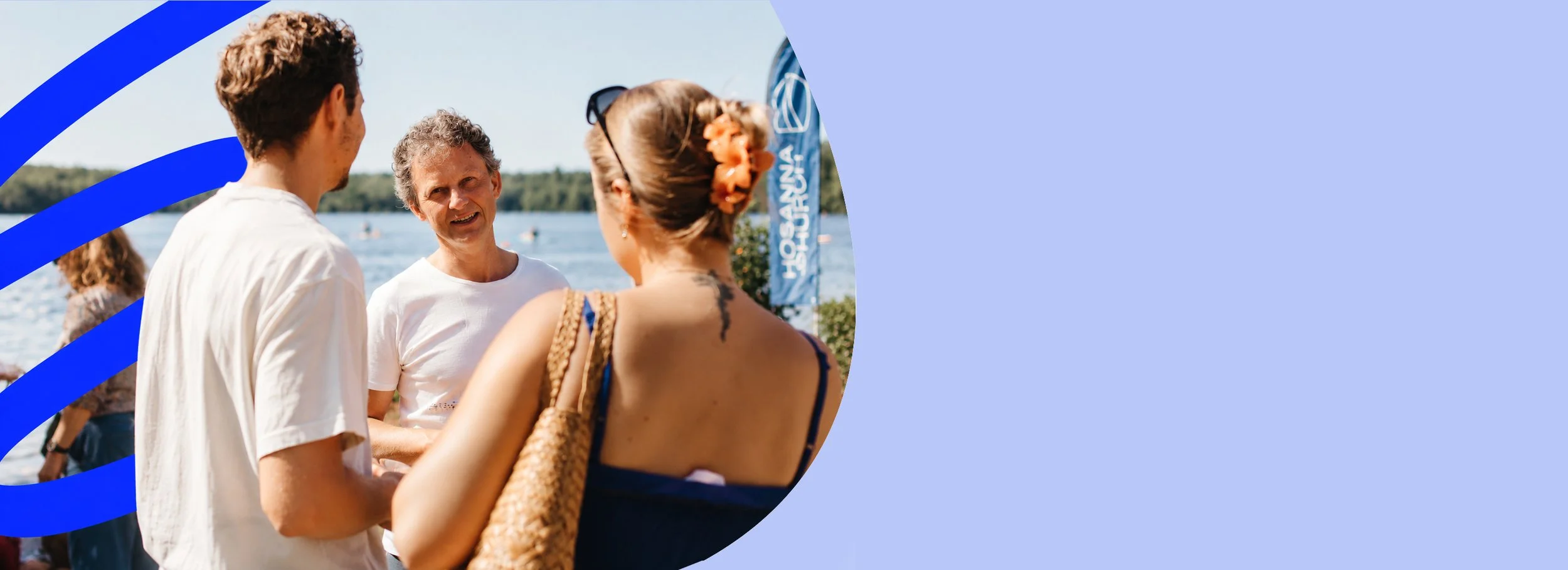 Menschen im Gespräch am Wasser bei sonnigem Wetter, in der Nähe eines blauen Fähnchens mit Text