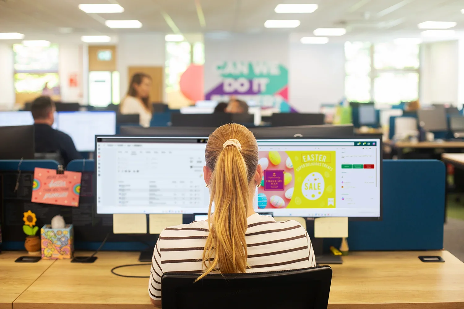 Woman in office looking at dual monitors