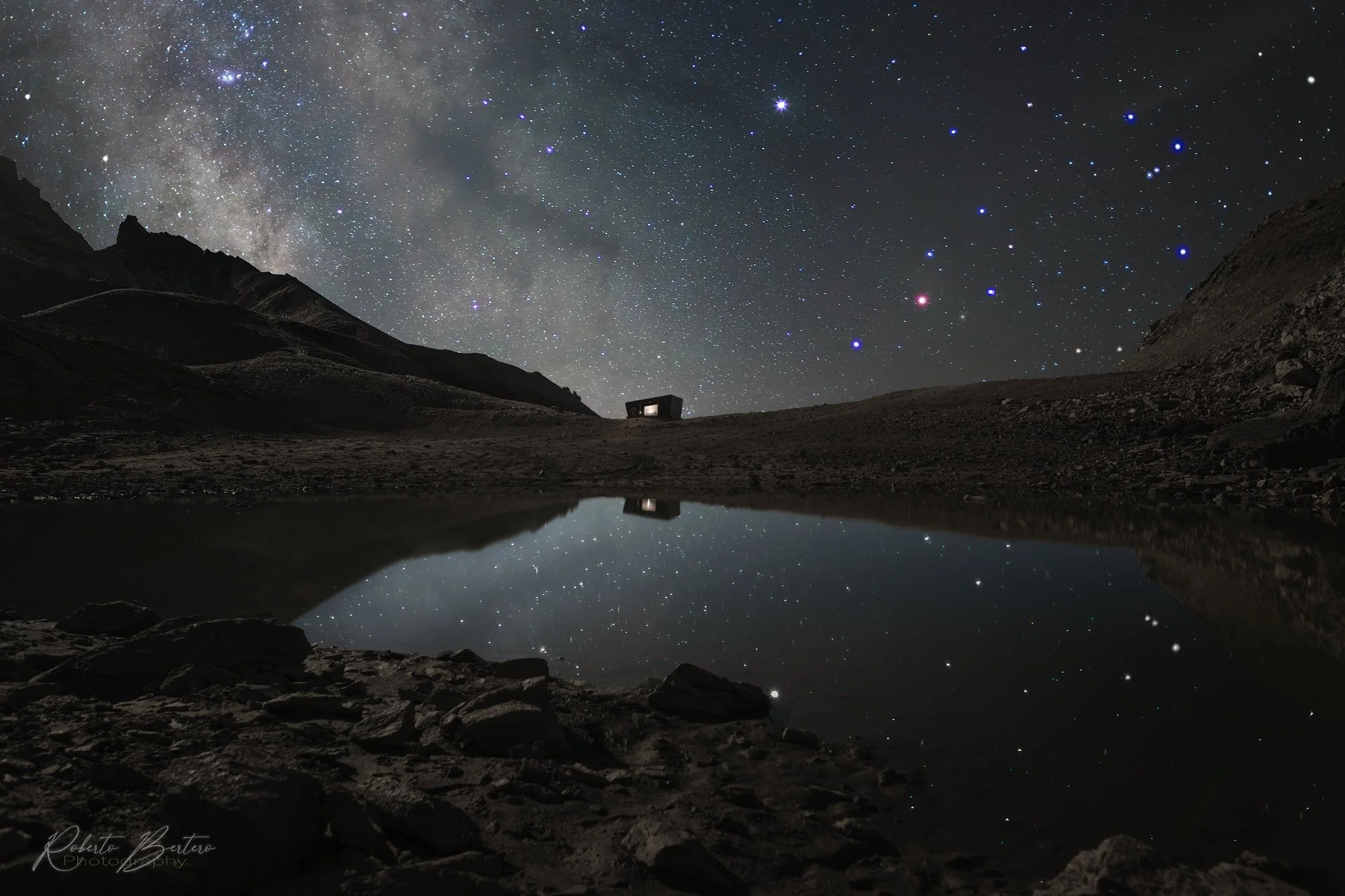 A starry sky mirroring into an alpine lake