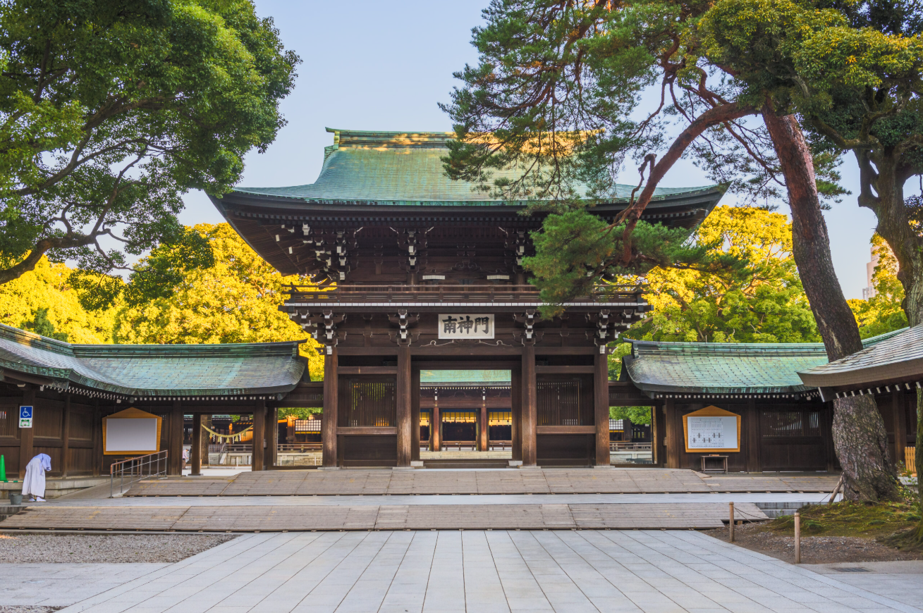 Traditional Japanese shrine gate (torii) surrounded by trees with green and yellow leaves.