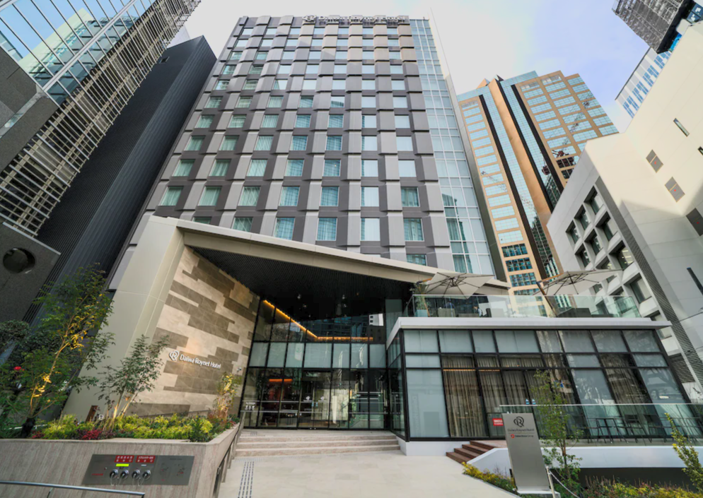 Tall modern hotel building with glass entrance and landscaping in an urban area