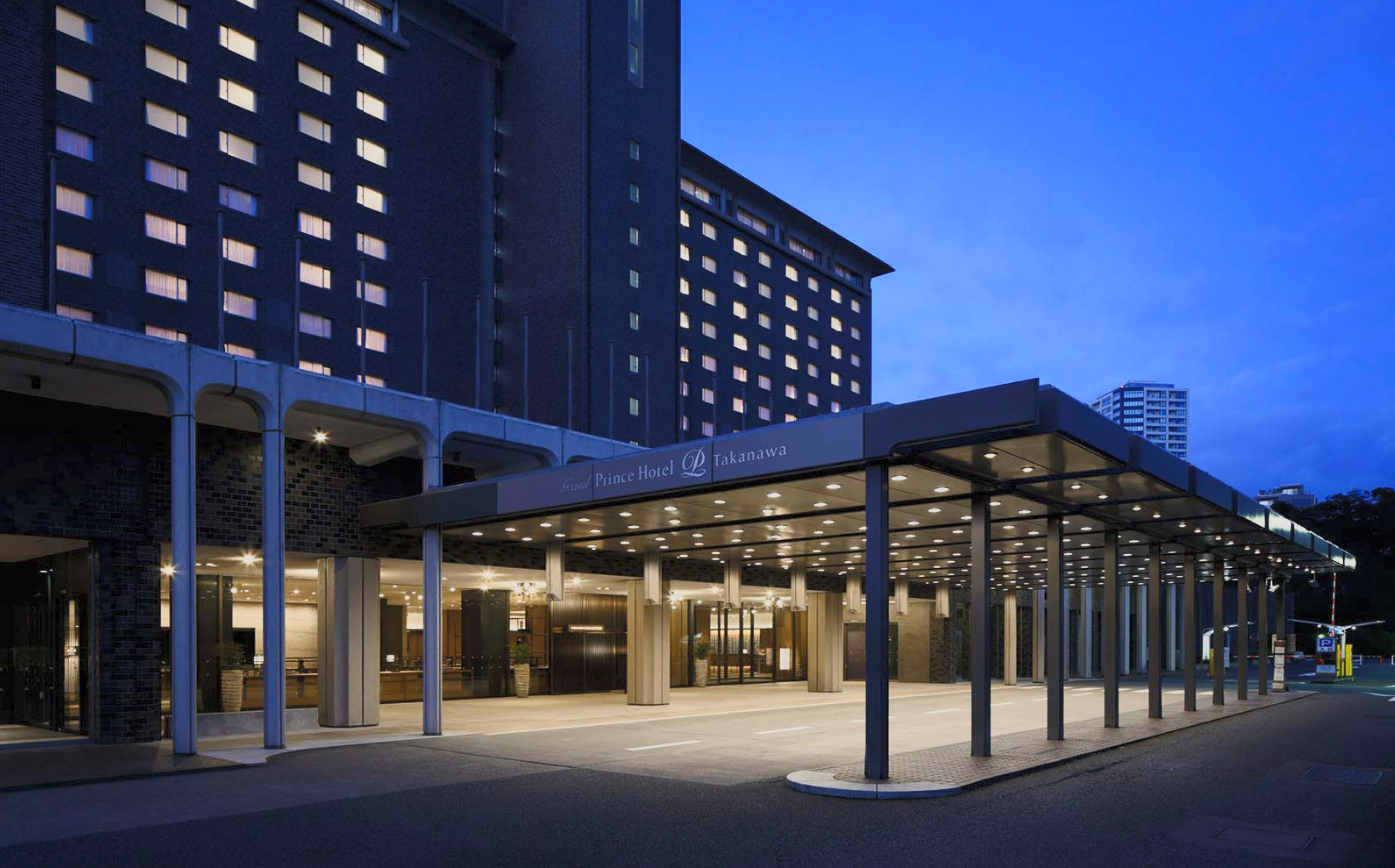 Night view of the entrance to Prince Hotel Takanawa with lit canopy and tall building background