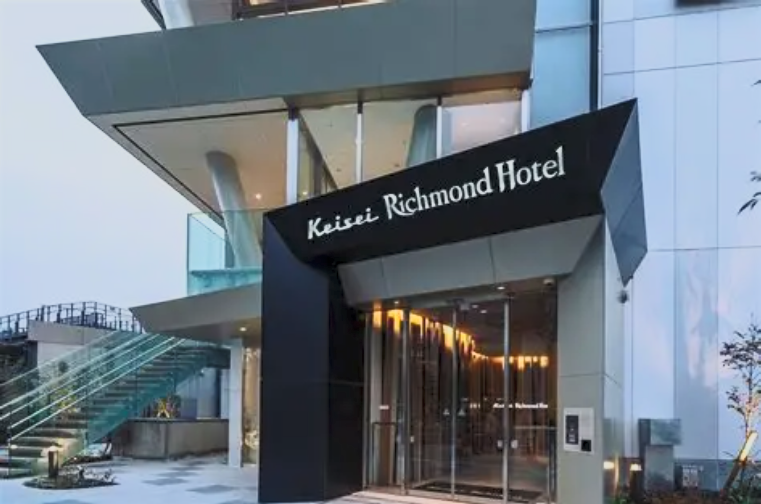 The entrance of the Keiisei Richmond Hotel with a modern design and glass doors.