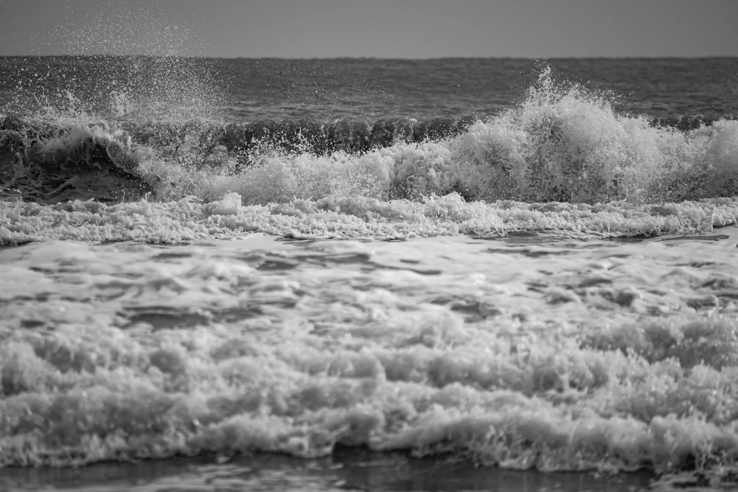 Black and white photo of ocean waves crashing on the shore.