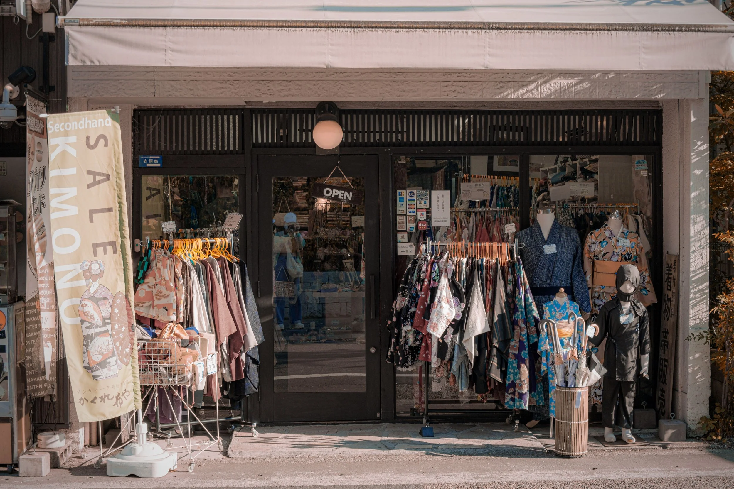 A storefront selling secondhand clothing, with racks of garments outside and an