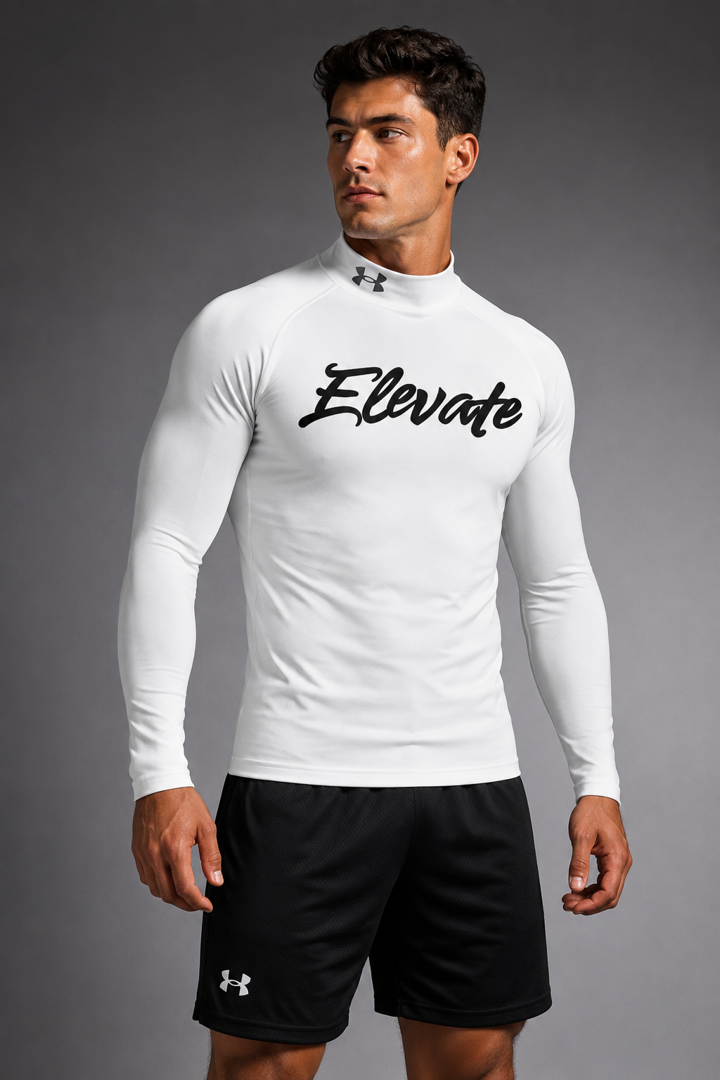 A man standing against a plain background, wearing a long-sleeve athletic shirt with the word 'Elevate' printed on it and black shorts with the Under Armour logo.