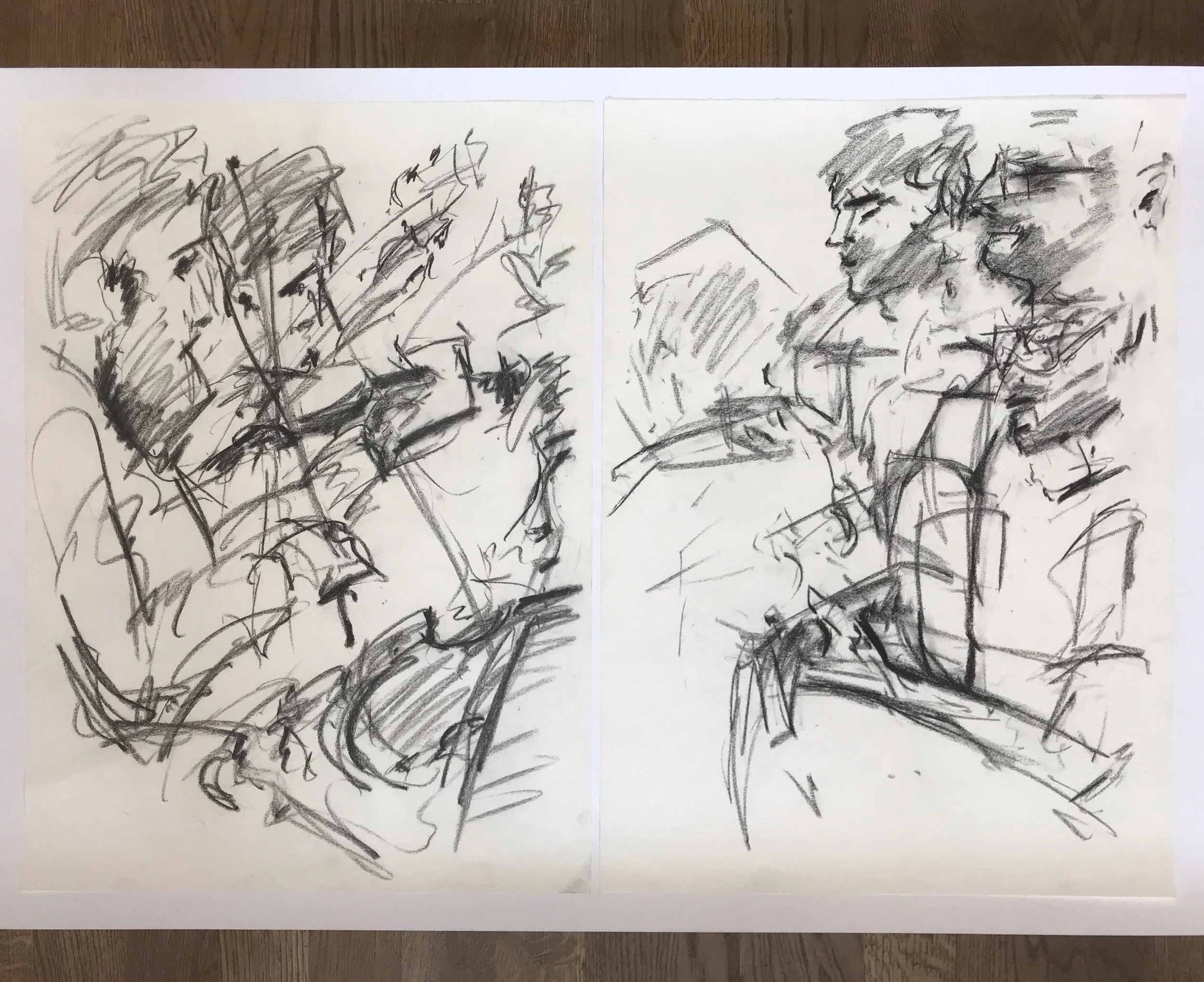Two abstract black-and-white sketches of human faces on separate sheets of paper, placed on a wooden surface.