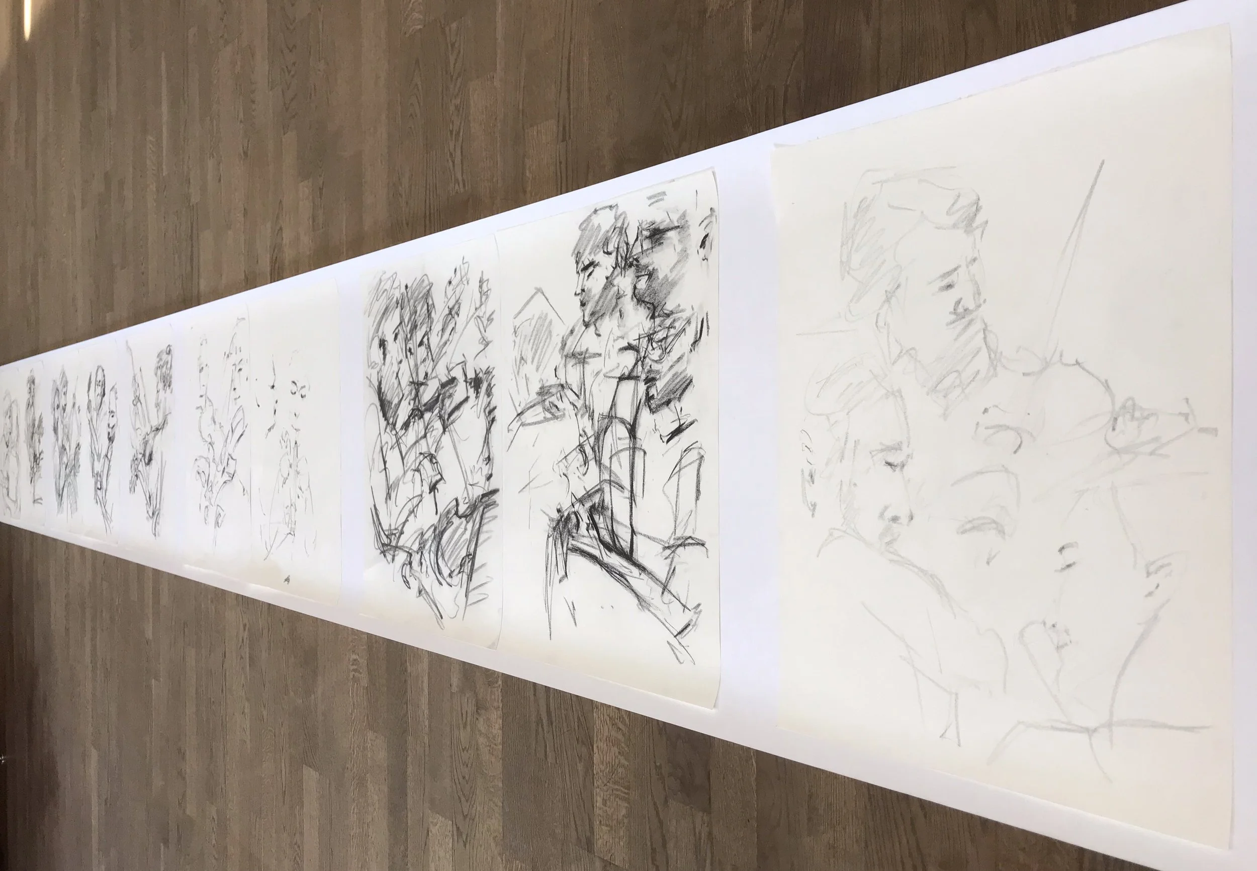 Large strip of paper on the floor with multiple sketch drawings of people and objects.