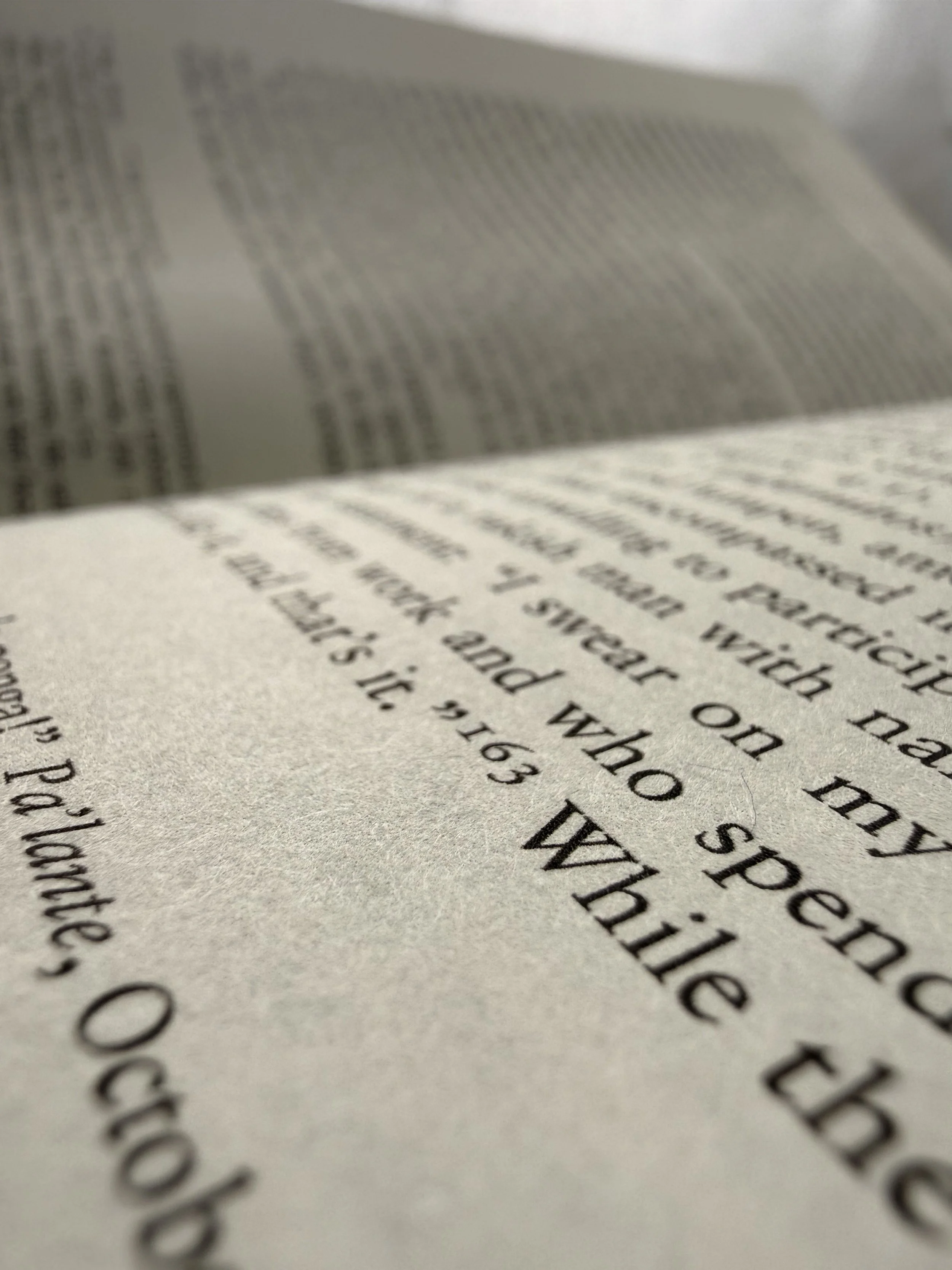 Close-up view of a printed book page with black text on off-white paper, slightly blurred and at an angle.